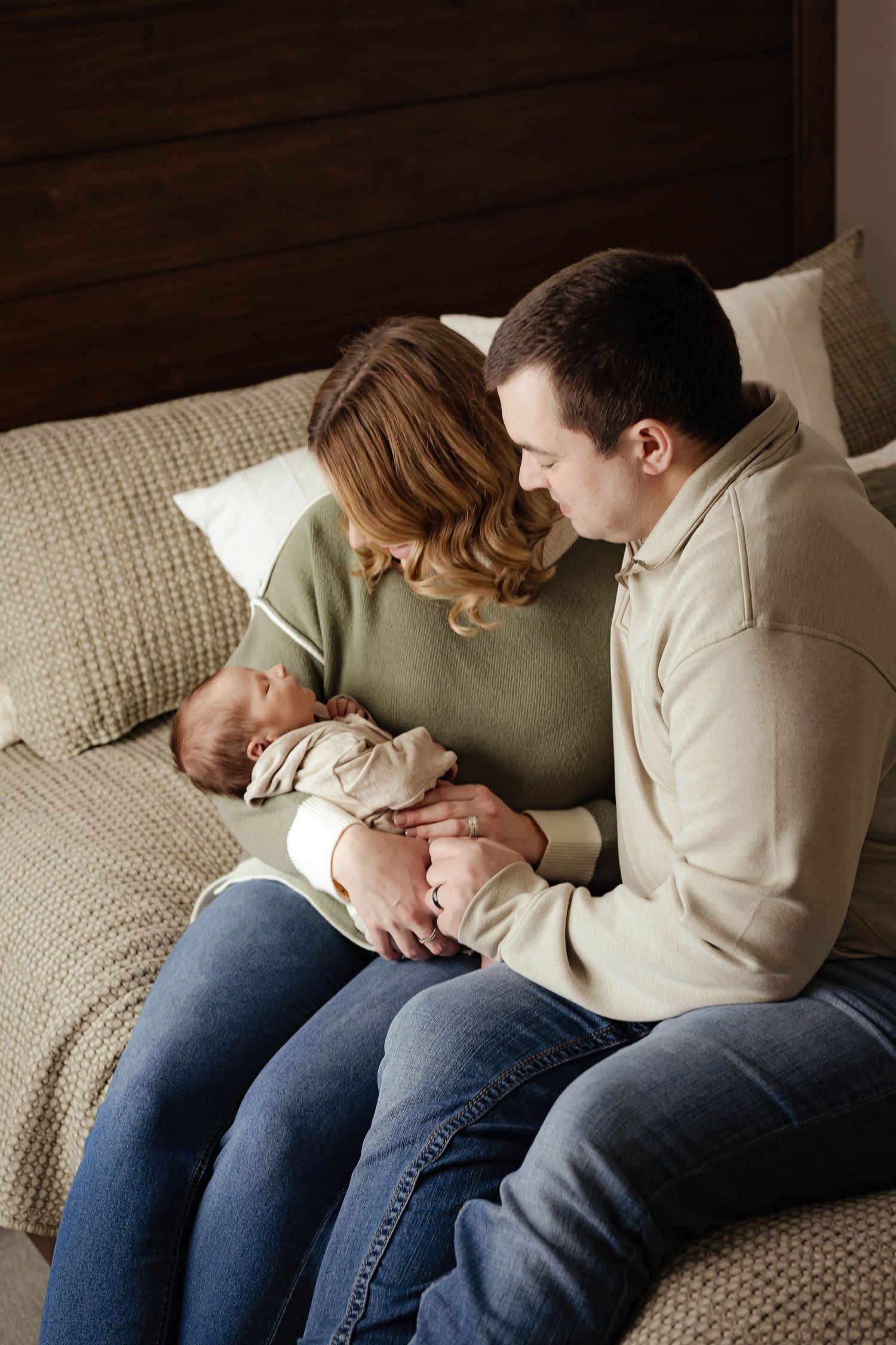 A person lies curled up on a beige couch wearing jeans and a light colored sweater in a series of connected photos.