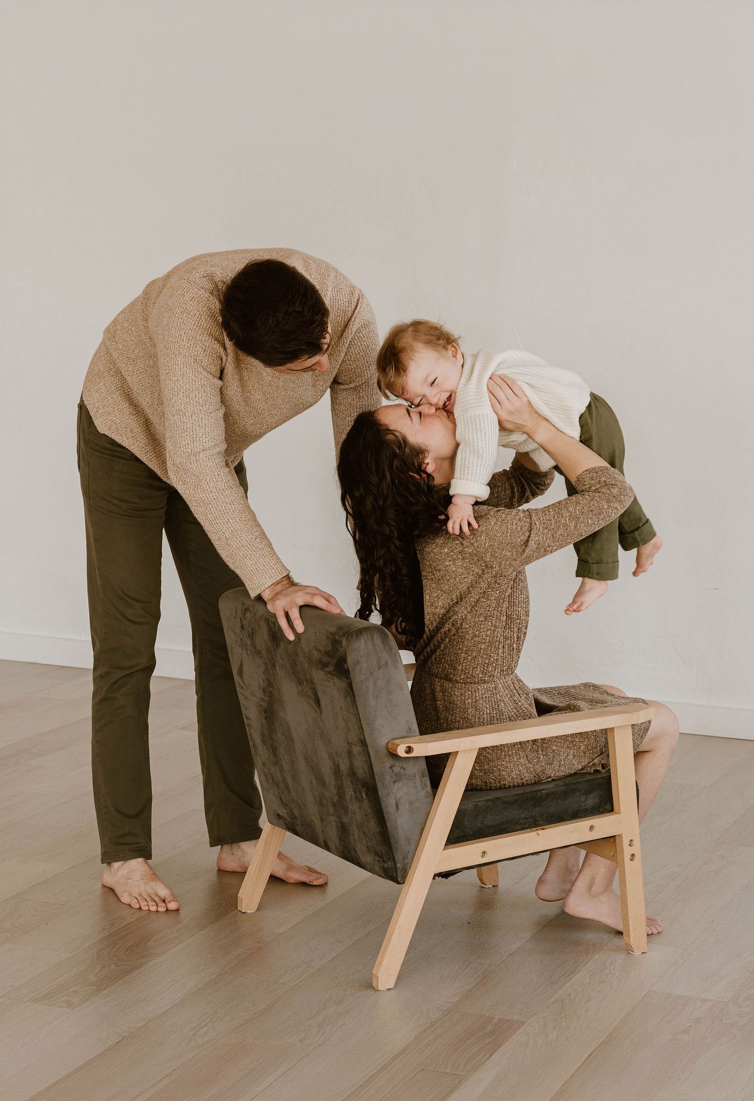 A series of four images showing someone assembling a minimalist wooden chair against a light gray background.