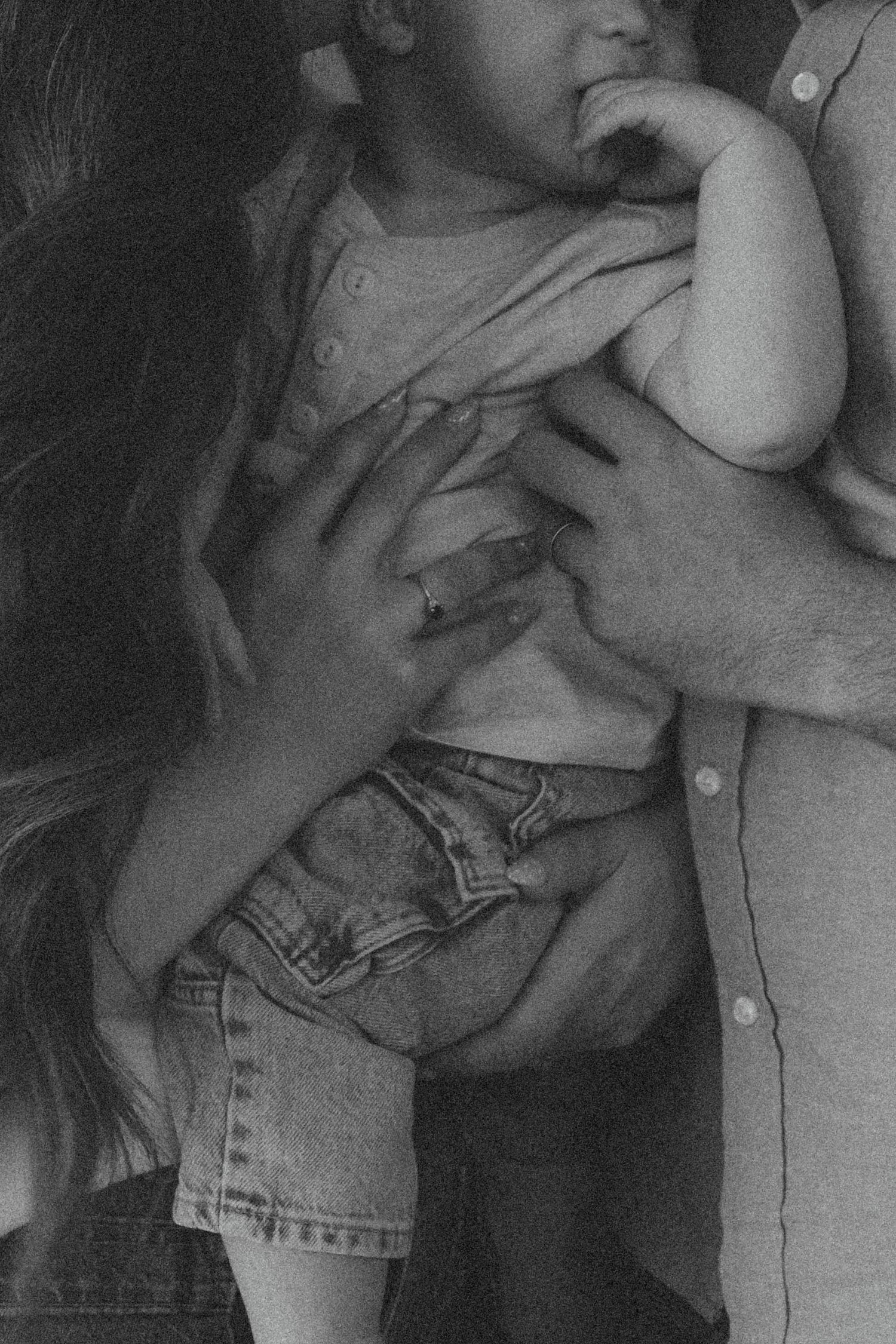 Black and white photo of parents holding a baby in denim shorts, capturing a tender family moment.