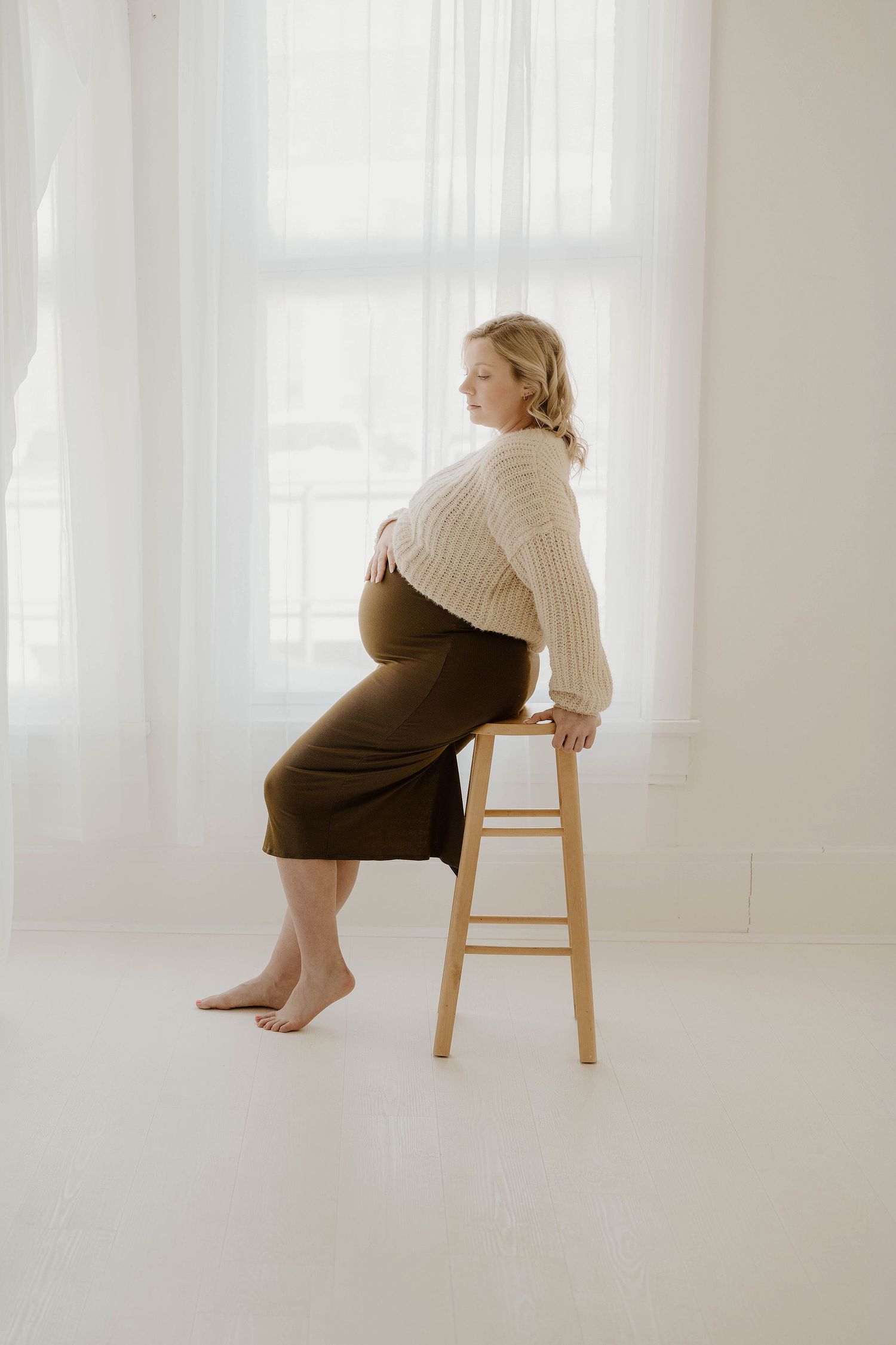 Artistic series of poses on a wooden chair showing a person in a cream sweater and dark skirt.