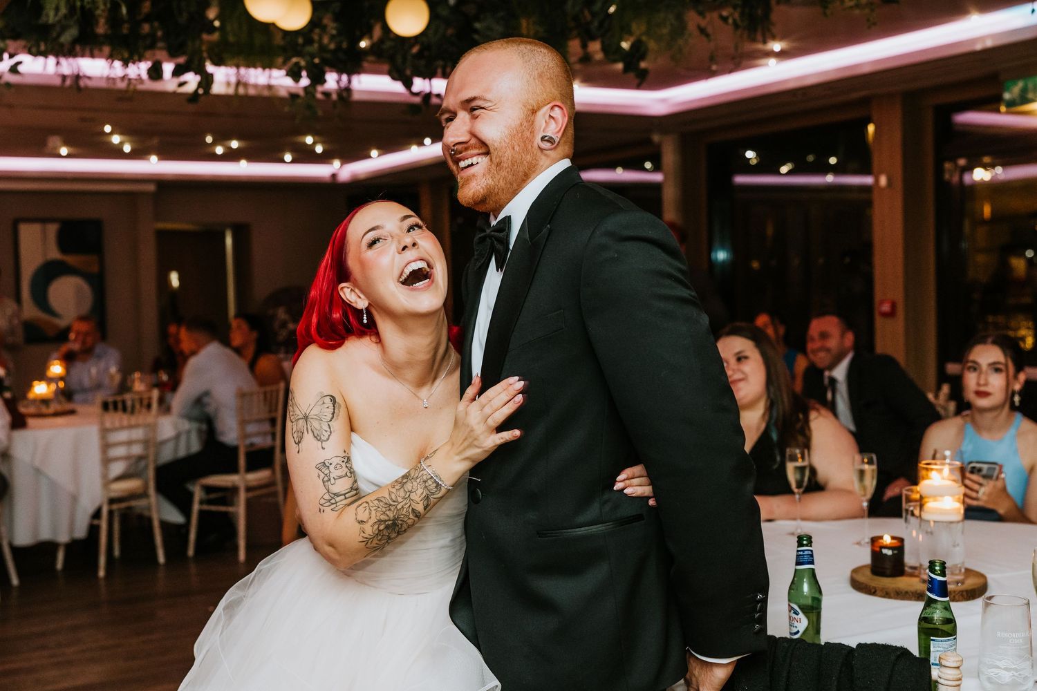 A couple shares a romantic dance moment at their wedding reception while guests look on in the background.