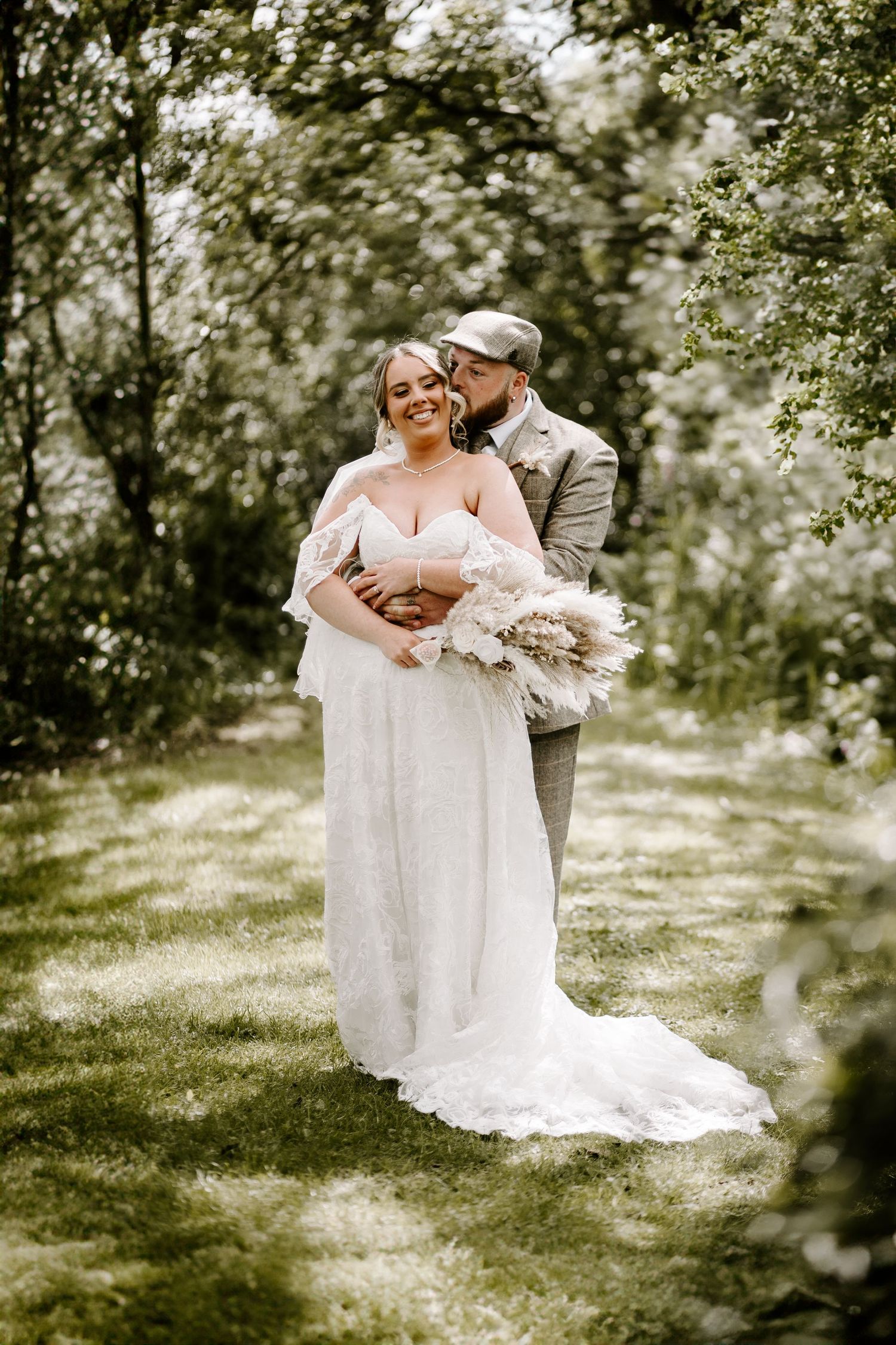 A couple embraces in a romantic outdoor garden setting with soft lighting and natural greenery.
