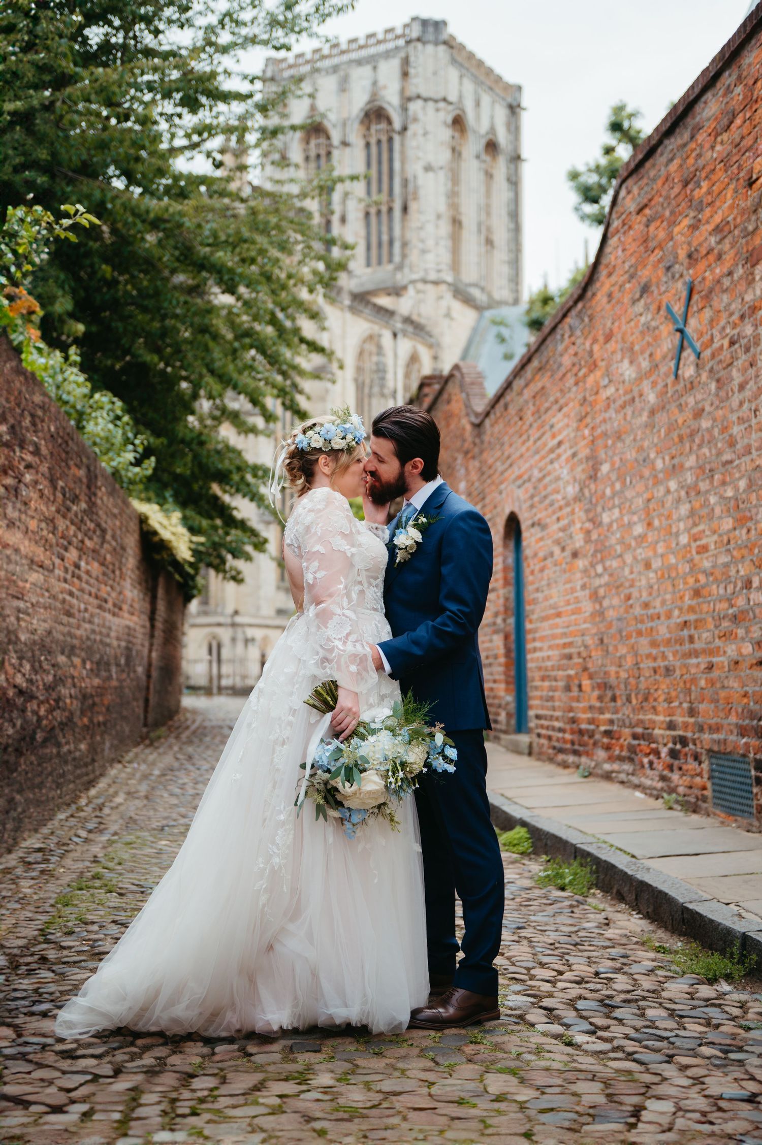 A romantic moment captured on a cobblestone path with historic brick walls and York Minister visible in the background.