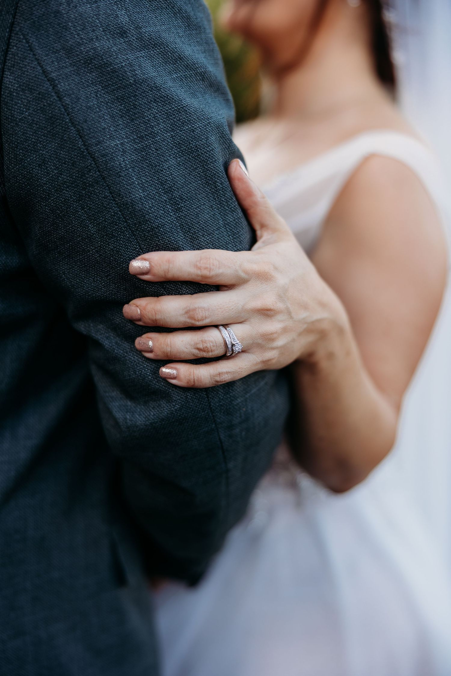 Close-up series of hands wearing wedding rings against dark suit and white dress fabric in intimate romantic poses.