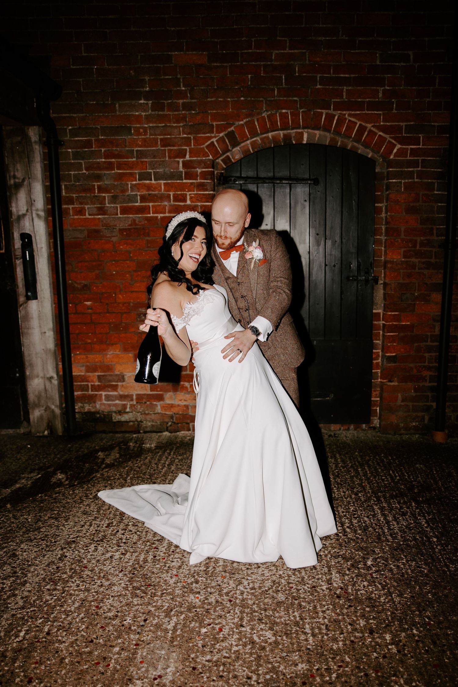 A couple dancing and dipping on a brick floor during their wedding celebration with rustic industrial decor in the background.
