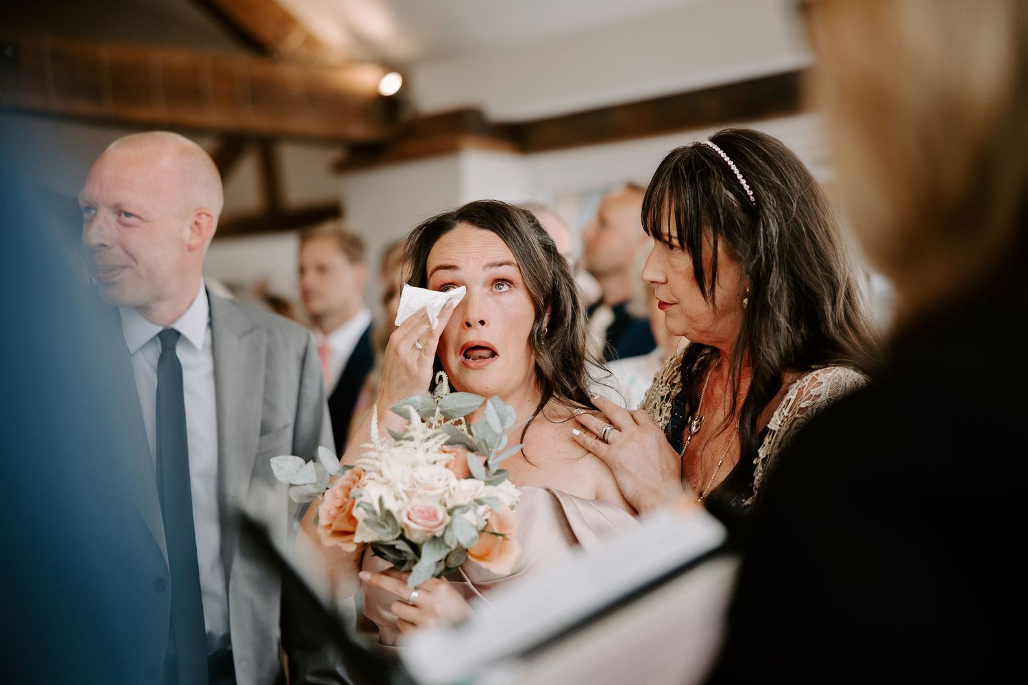A happy couple and their loved ones share heartfelt laughter during a beautiful outdoor wedding celebration.