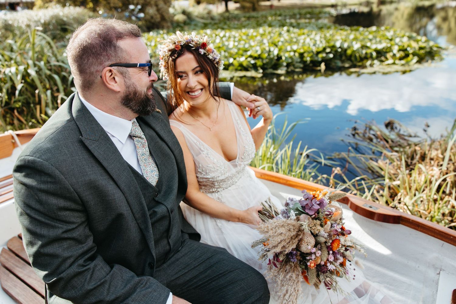 Bride and groom share a tender moment during an outdoor waterfront wedding ceremony at sunset.