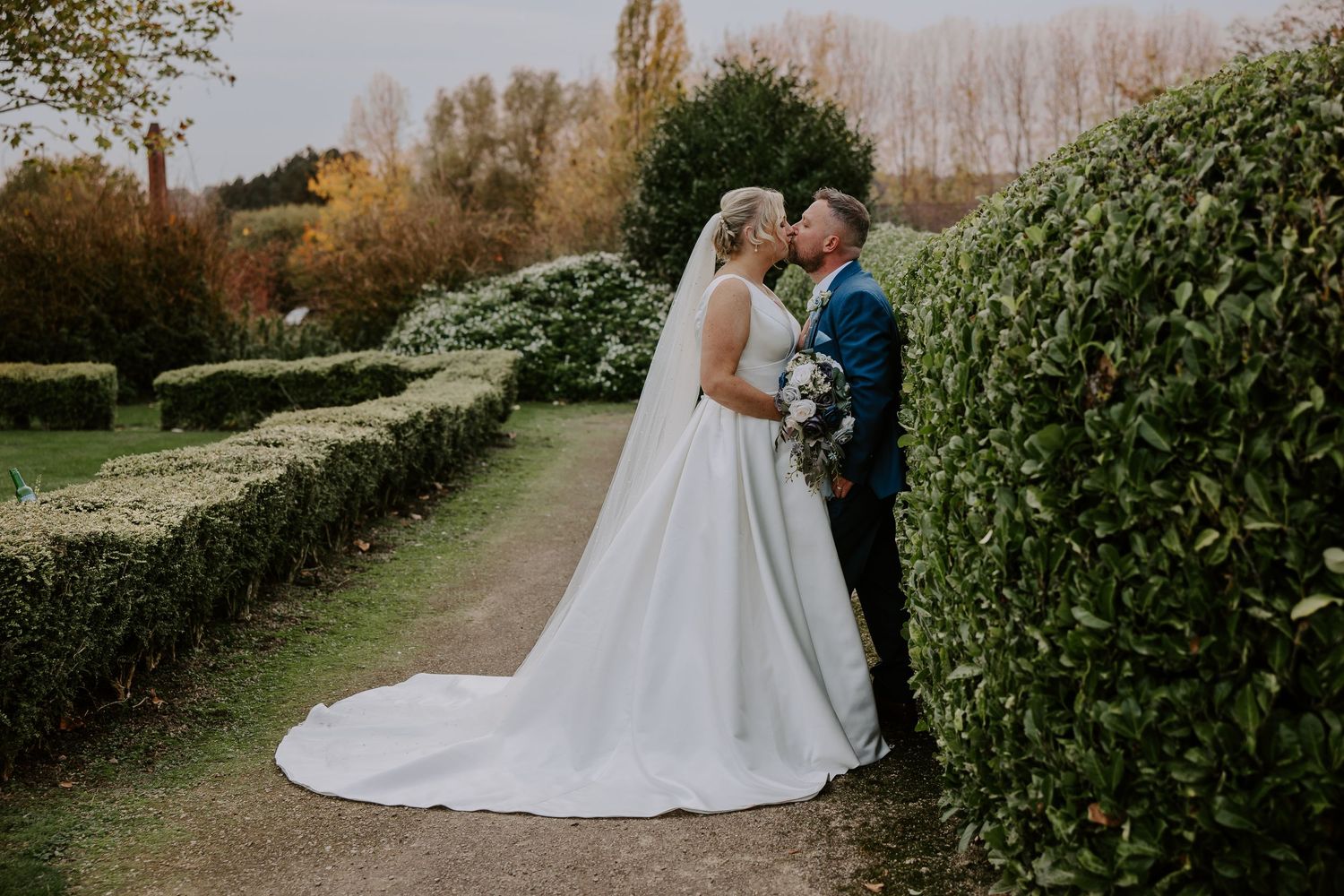 Couple in elegant wedding attire share romantic moments in a lush garden setting during golden hour.