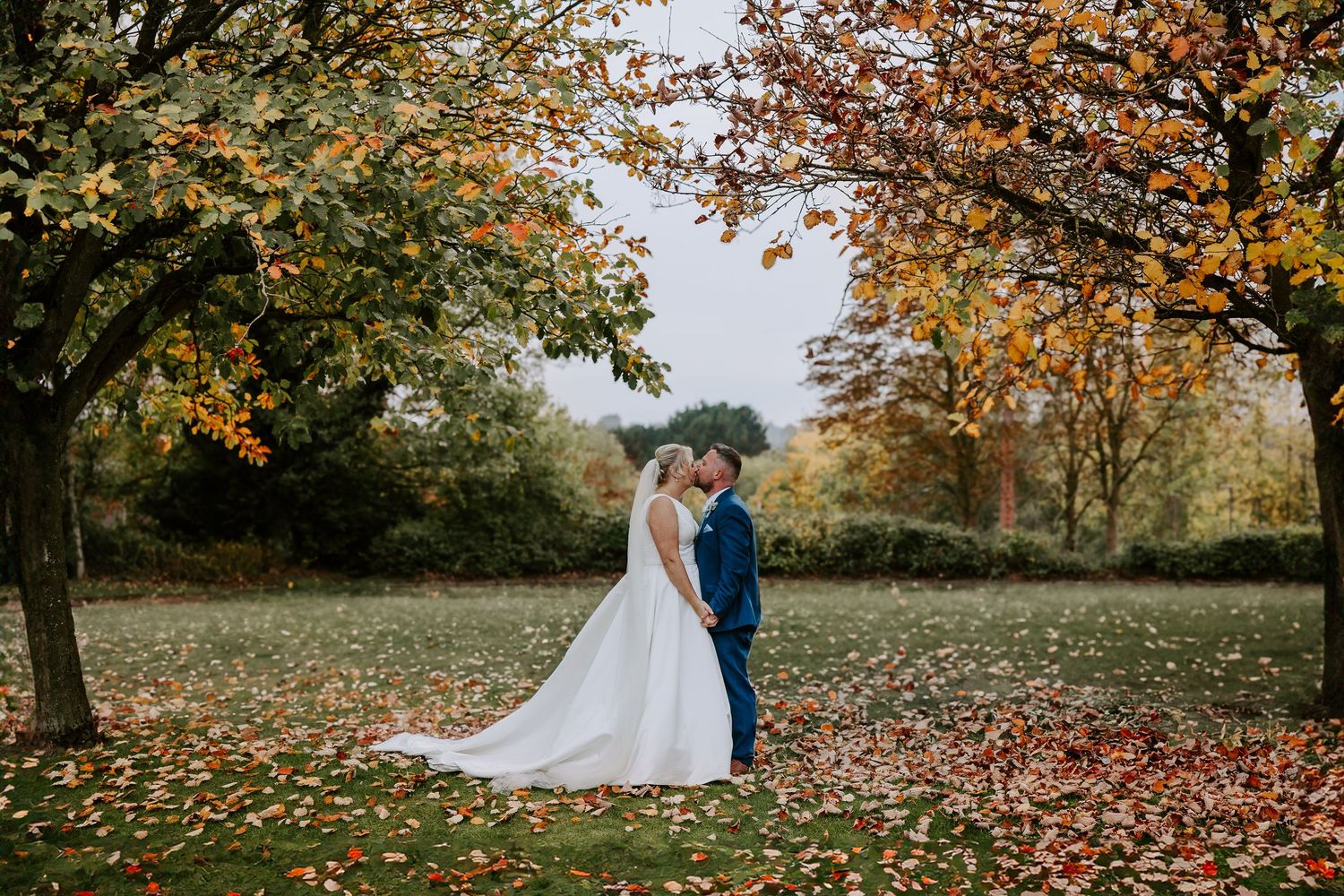 Couple celebrates their wedding day surrounded by vibrant autumn foliage in a scenic outdoor setting.