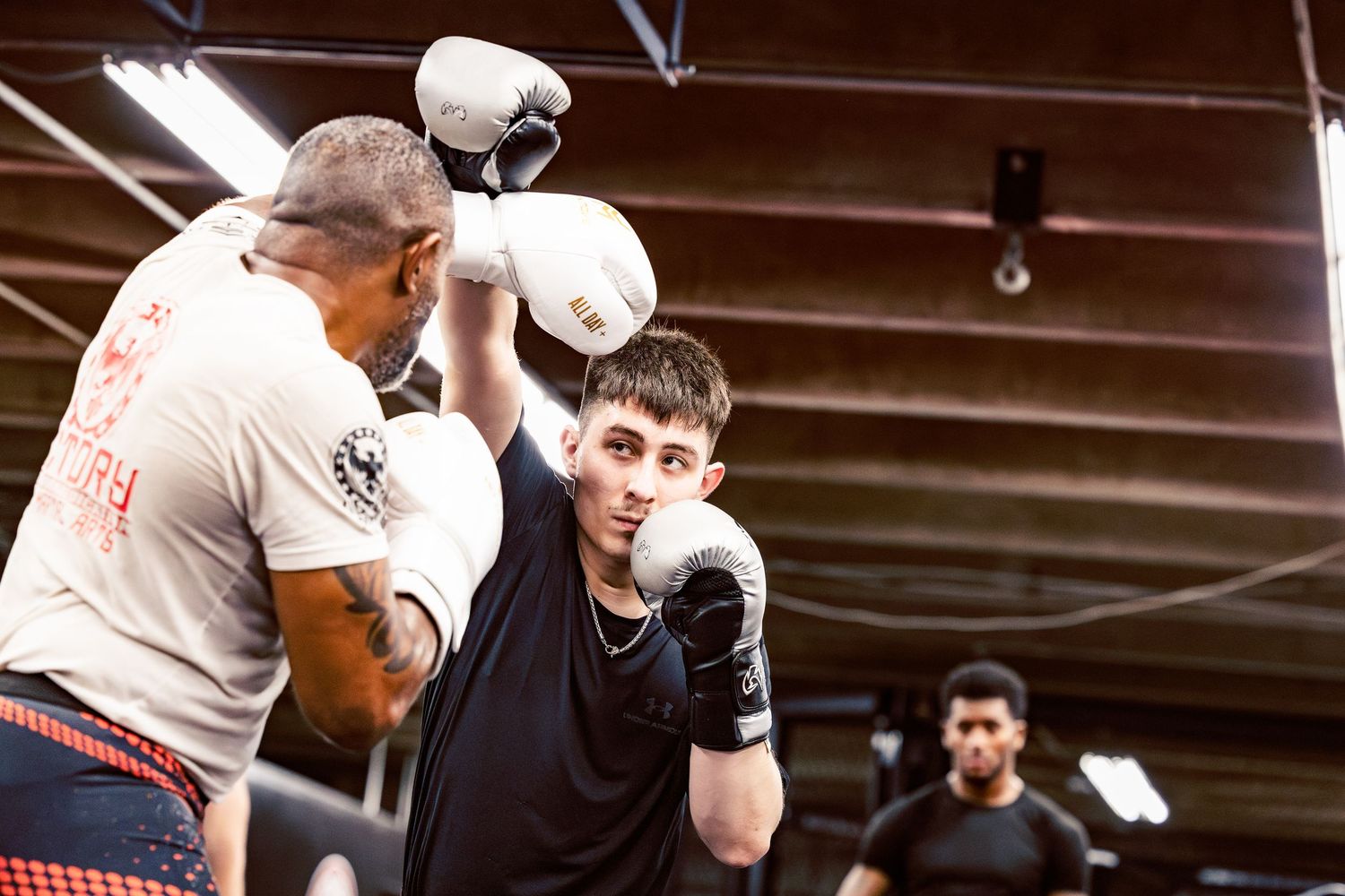 Combat sports athletes training in a gym with boxing gloves and protective gear.
