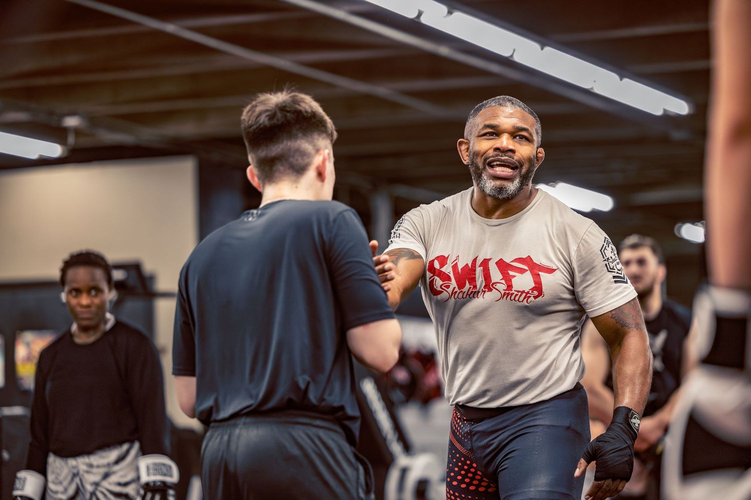 Athletes practicing combat sports techniques during an intense training session in a professional gym setting.