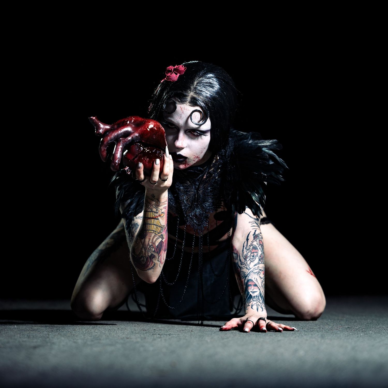 Gothic Snow White cosplay with tattoos holding a red apple in dramatic dark studio photography.