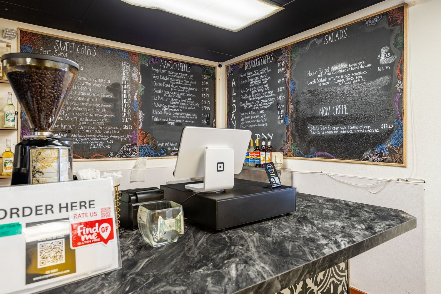 Order counter with POS system and chalkboard menu at Crepe Amour CO cafe.