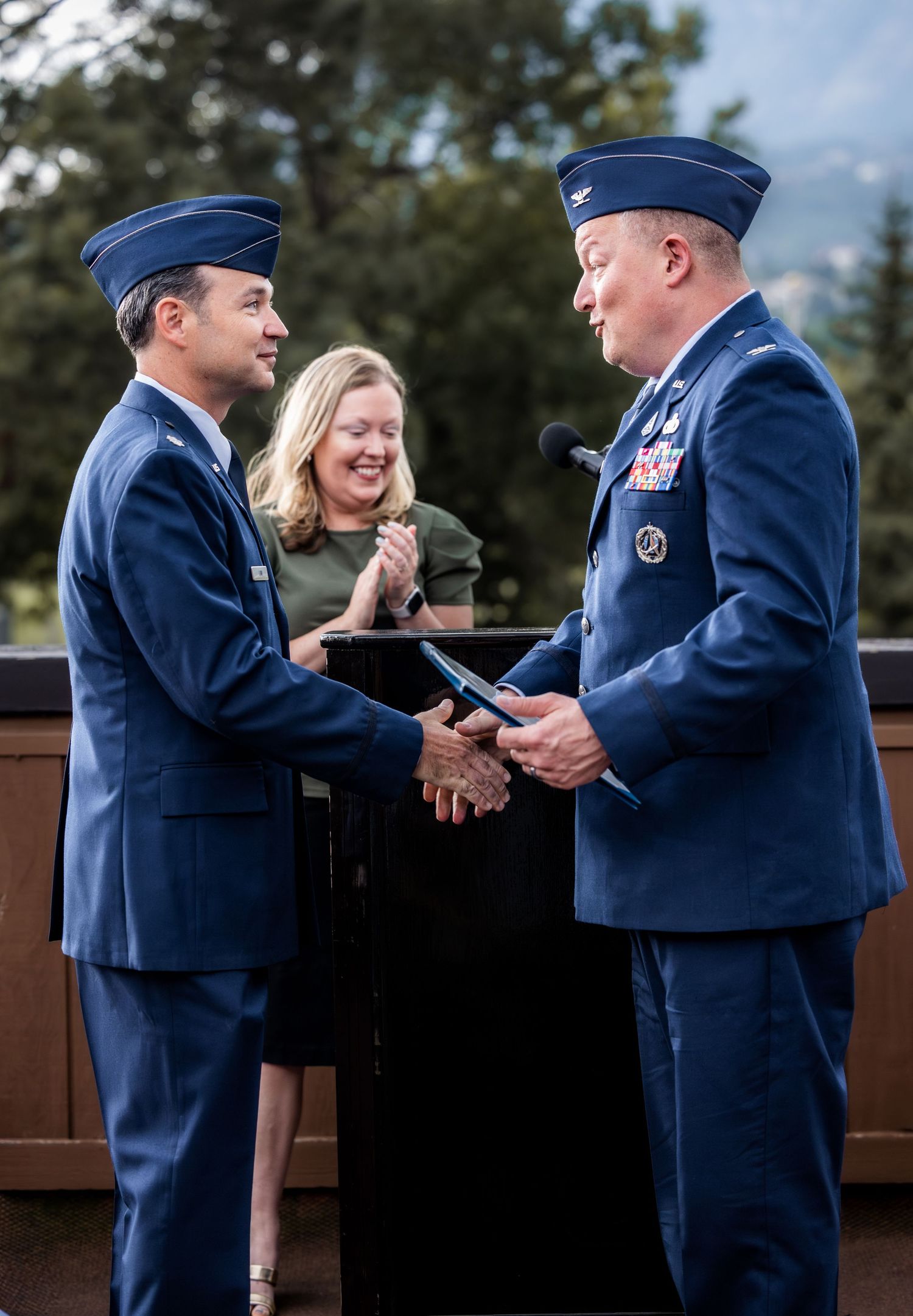 Air Force service members exchanging ceremonial items during formal outdoor event.