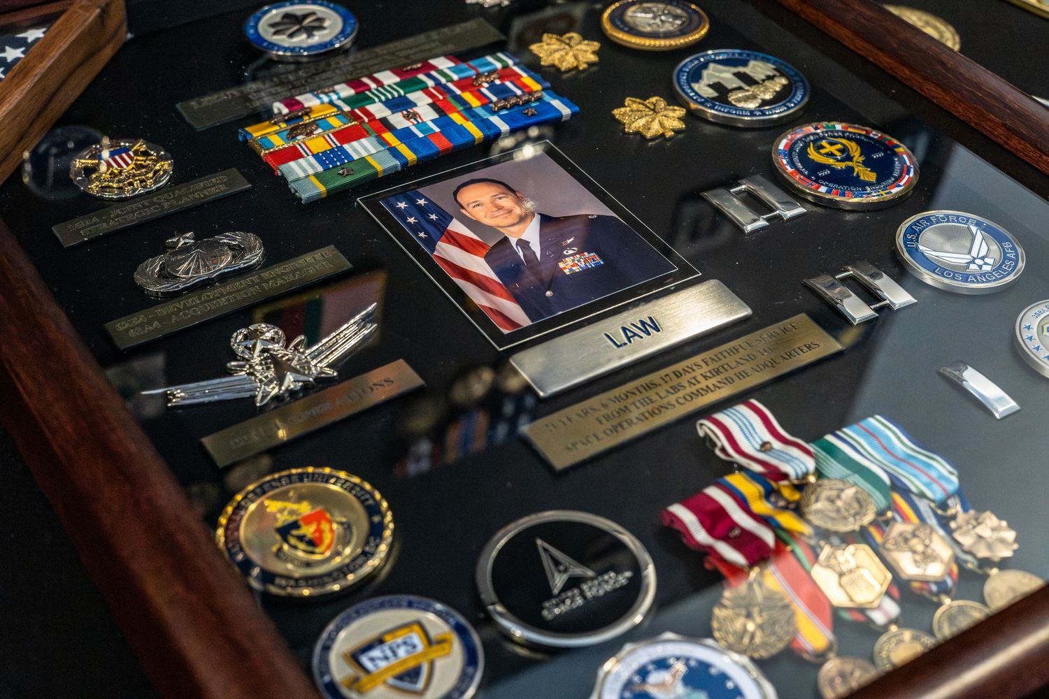 Military medals, ribbons, and service awards displayed in a wooden shadow box case.