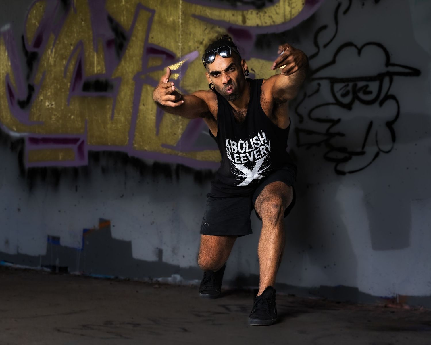A sequence of dance moves captured in a dark urban setting with graffiti walls in the background.