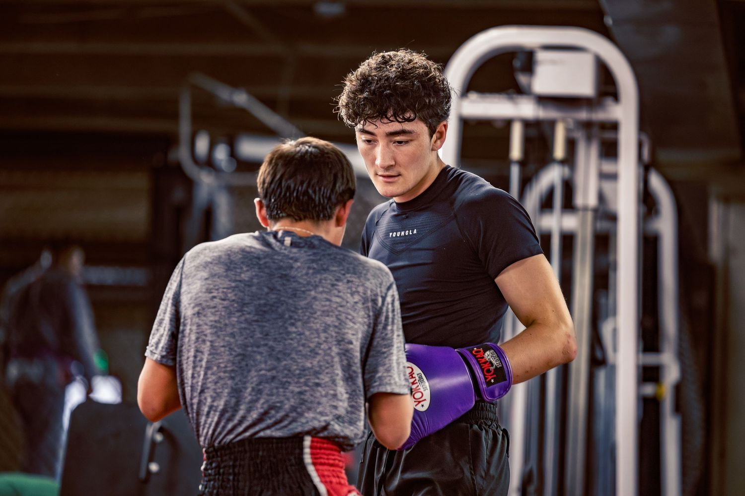 Mixed martial arts athletes training together in a well-equipped combat sports facility.
