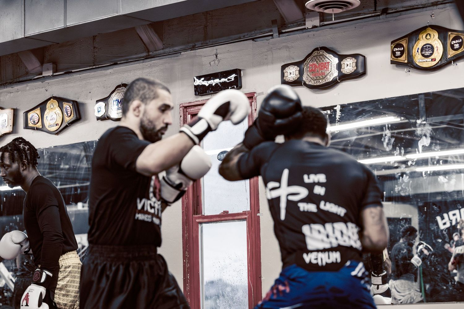 Boxers training in a gym with championship belts displayed on the wall.