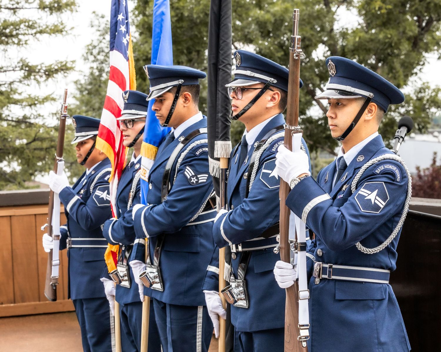 Military honor guard in blue uniforms holding flags during ceremonial formation.