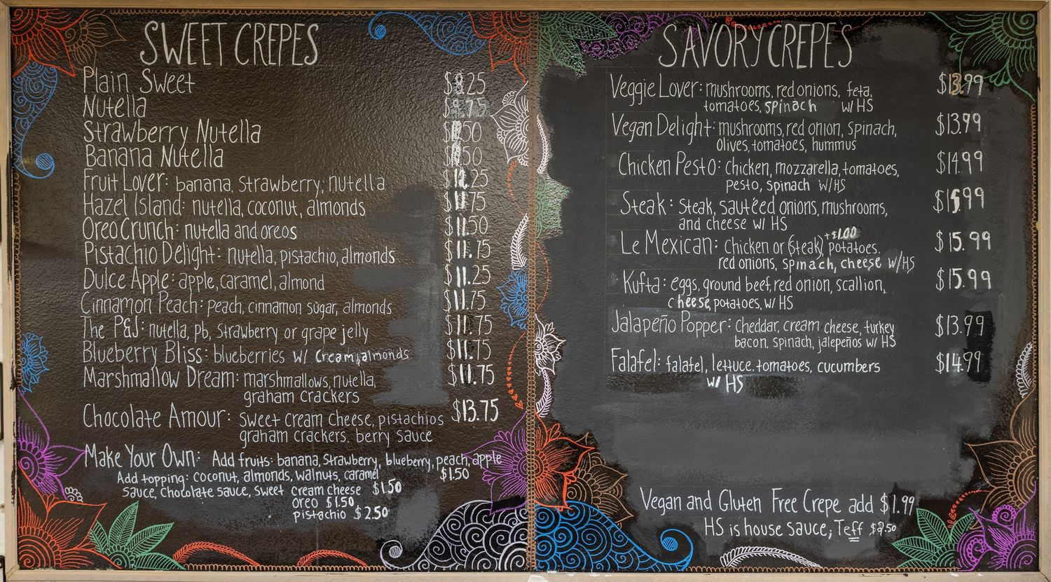 Chalkboard menu displaying sweet and savory crepes with prices at a cafe restaurant.