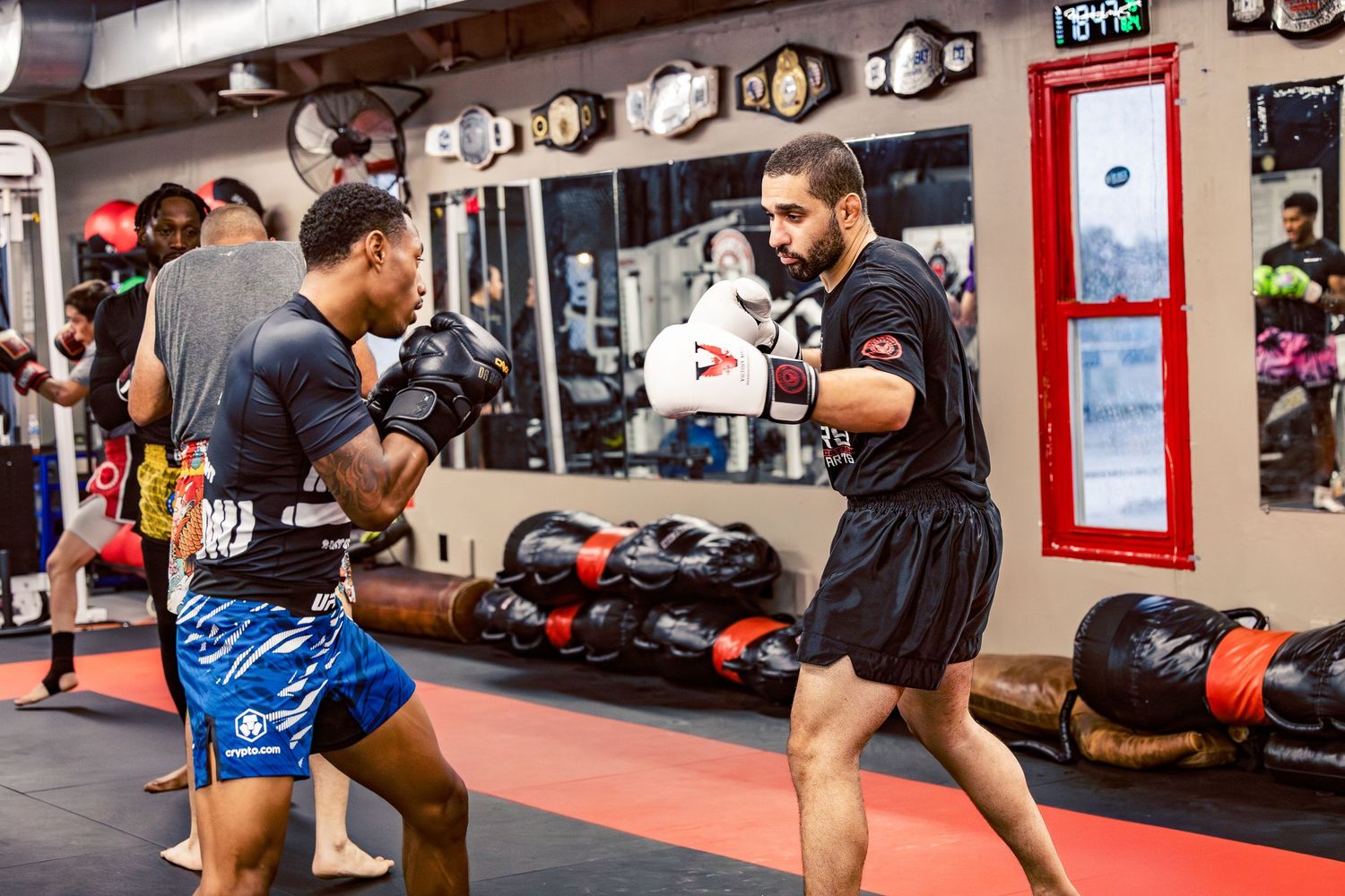 Combat sports gym interior with students practicing along the wall.
