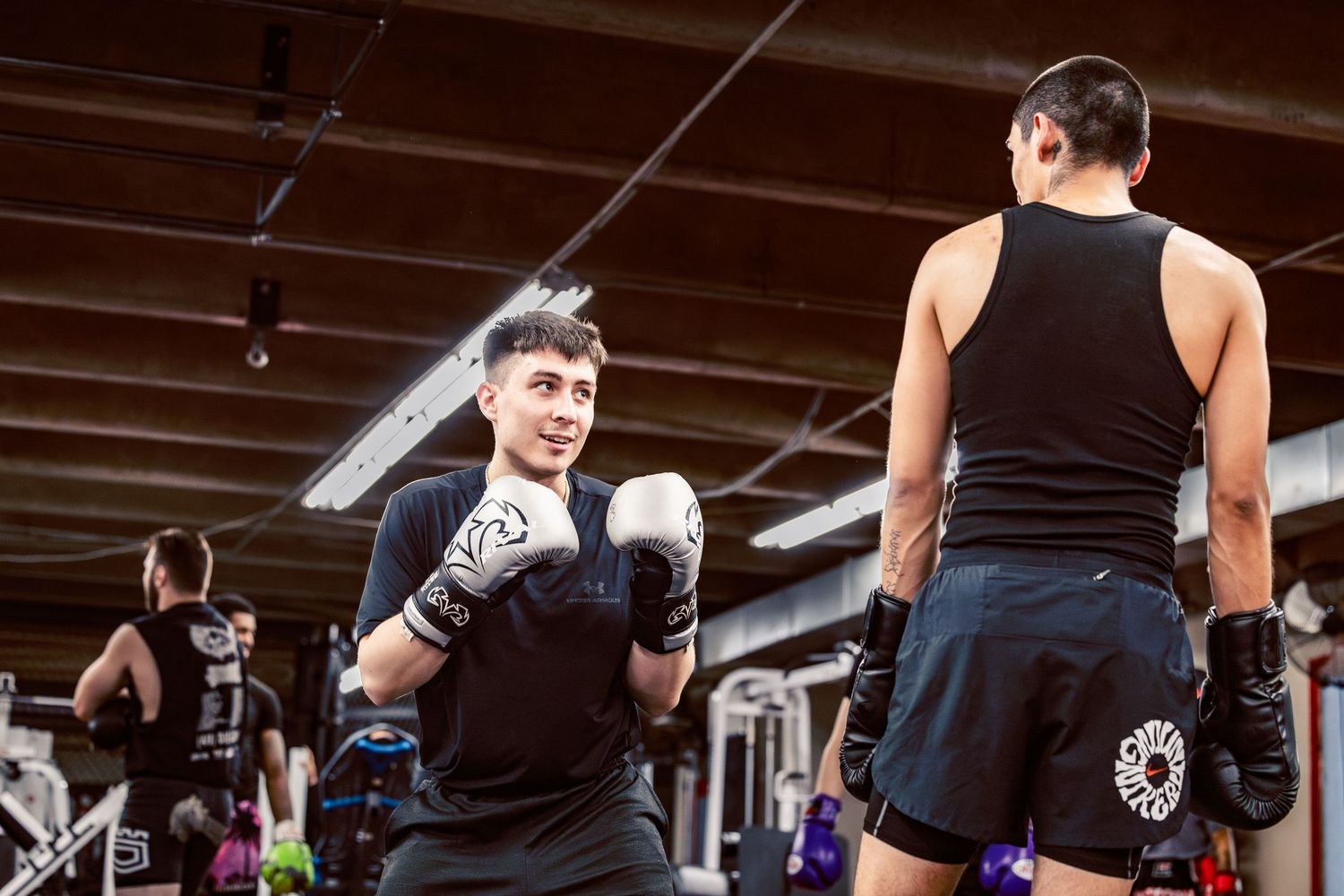 Athletes practicing boxing moves and footwork in a martial arts gym.