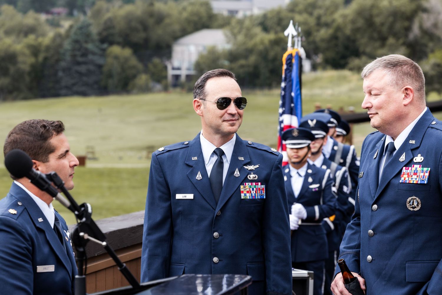 Military service members in dress blues gathered for formal outdoor ceremony.