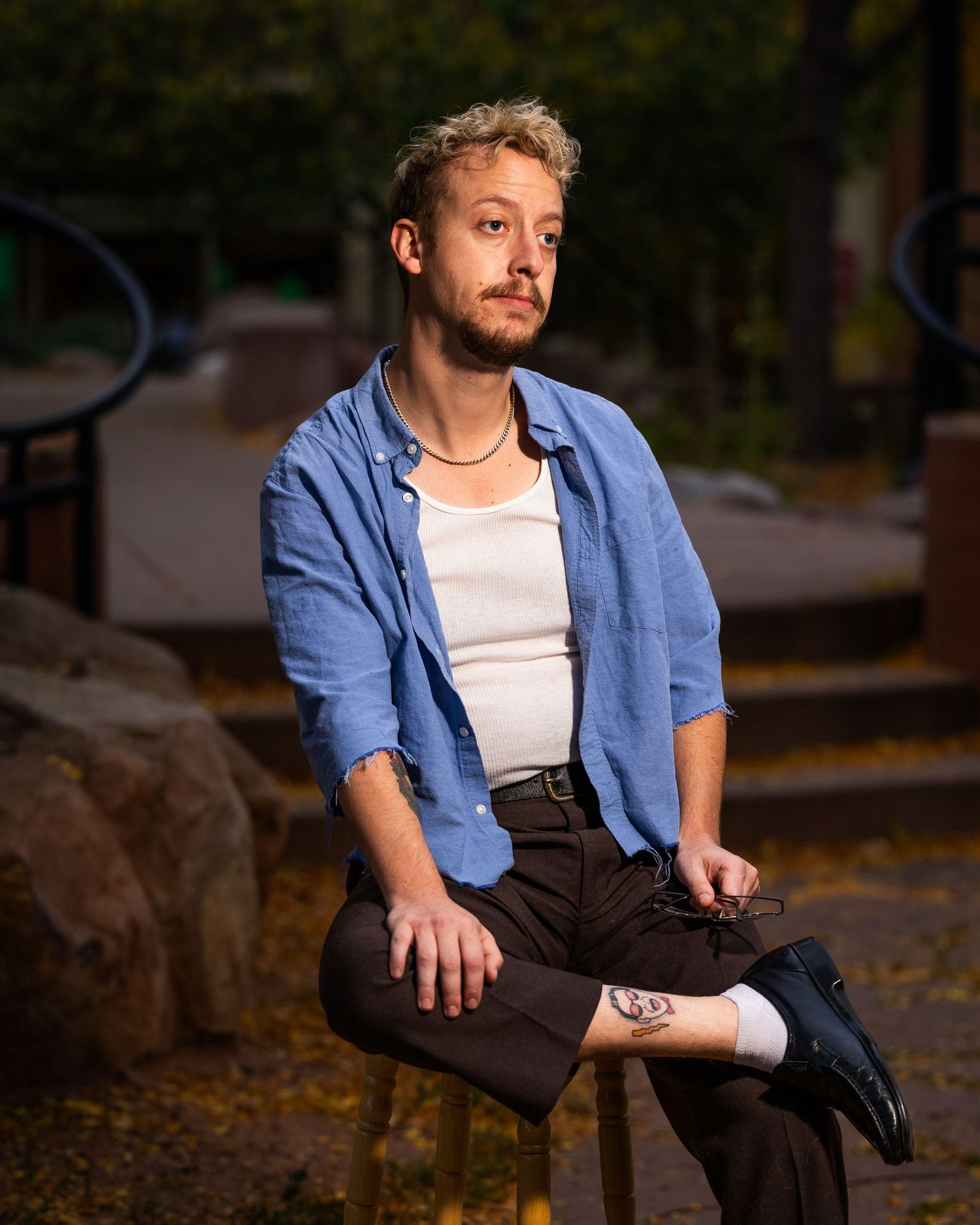A series of casual outdoor poses showing someone in blue denim and dark pants against a natural background.