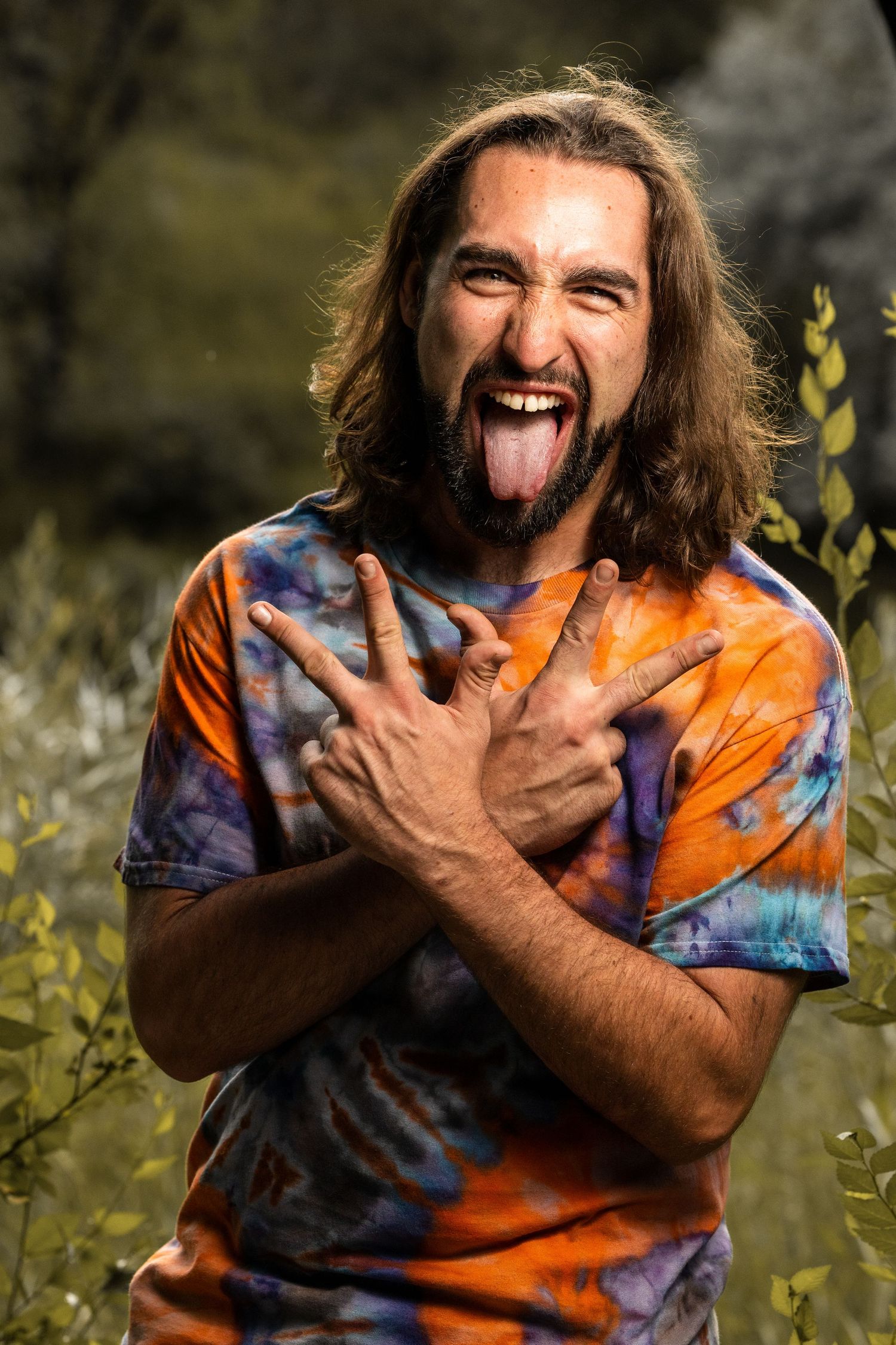 Energetic portrait of someone in tie-dye making an expressive face outdoors.