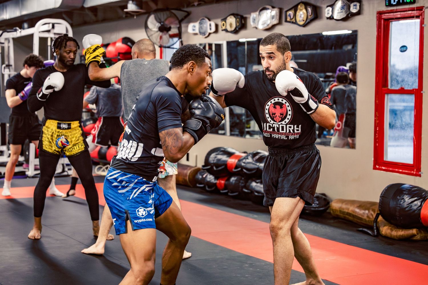 Kickboxing practitioners working on fight techniques in a professional training environment.