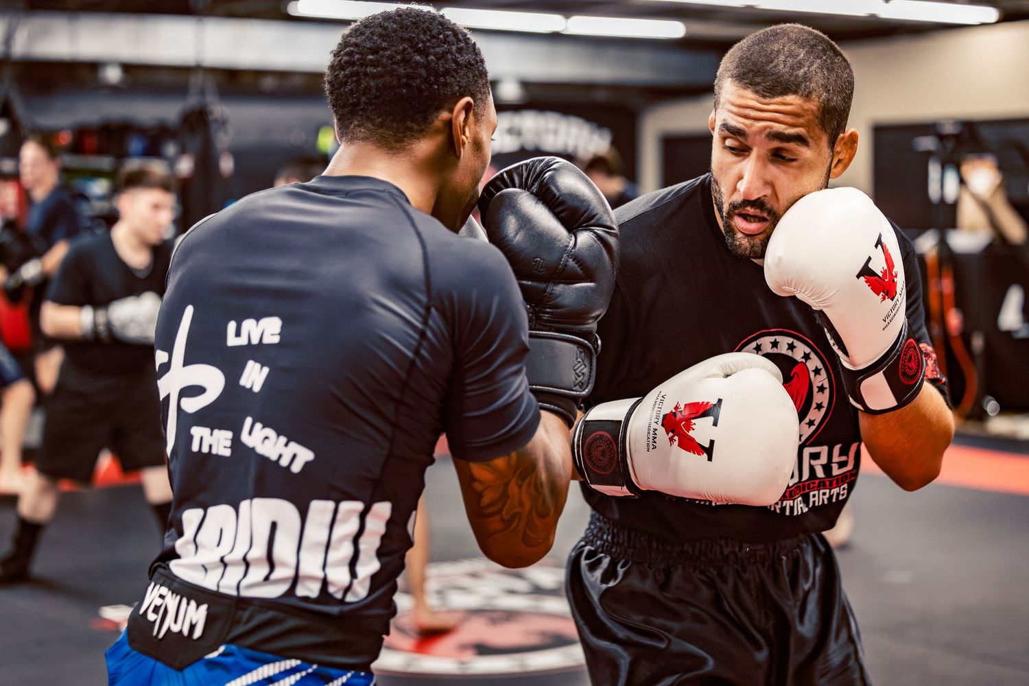 Combat sports enthusiasts practicing defensive moves and counterpunches during group training.
