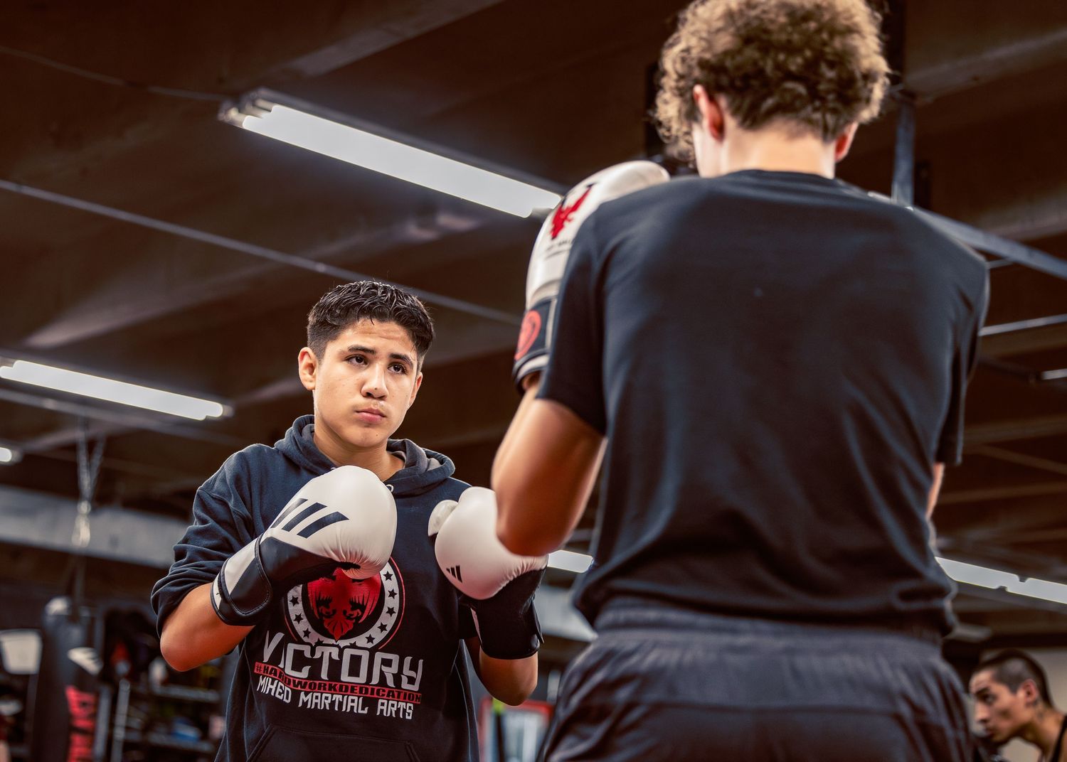 Boxing students practicing defensive moves during an indoor training session.