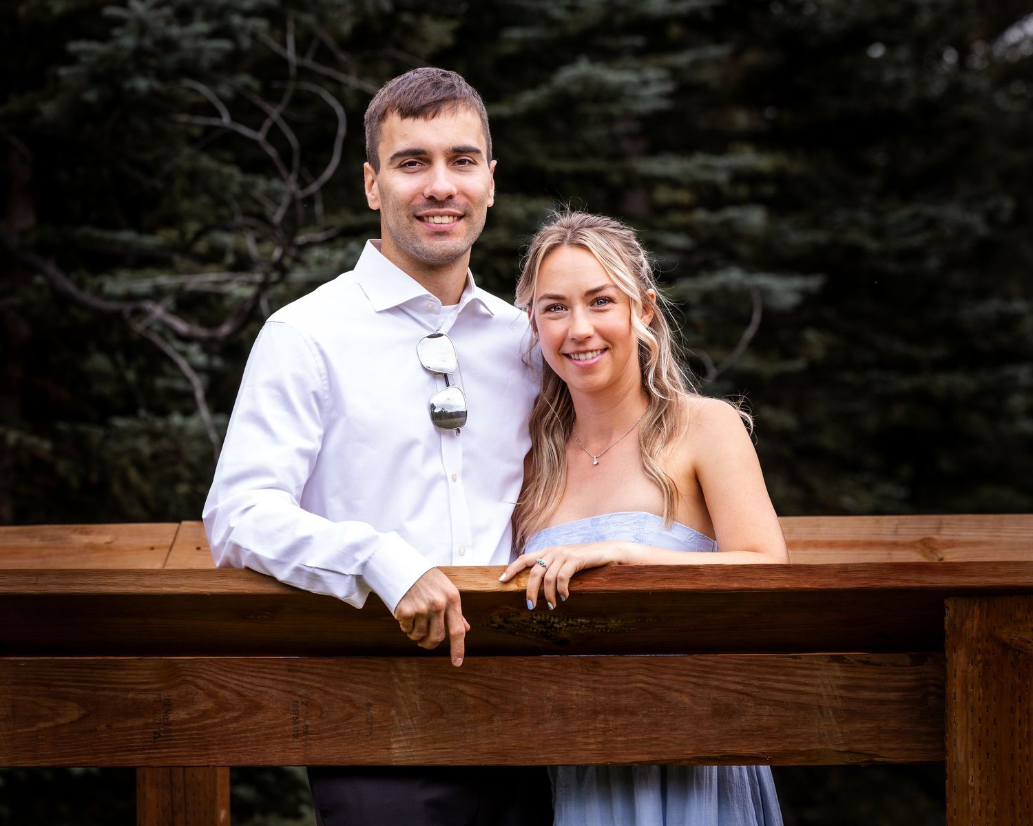 Romantic couple sharing tender moments on a wooden deck surrounded by evergreen trees.