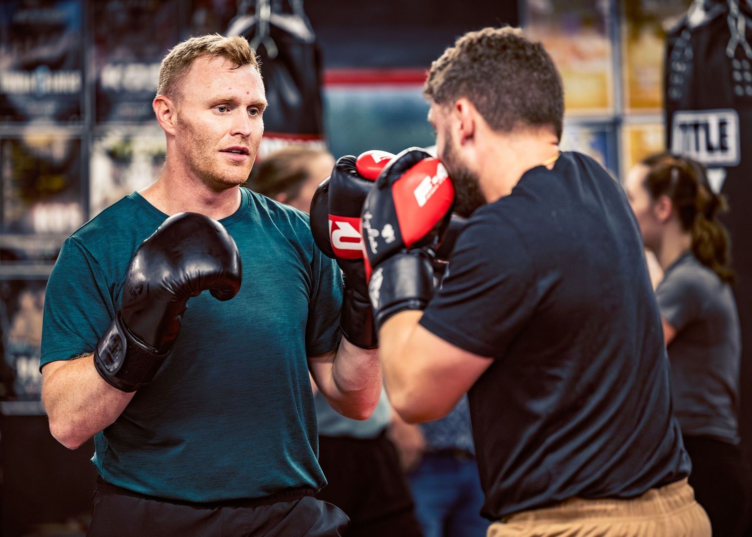 Two people practicing boxing moves in an indoor training facility.