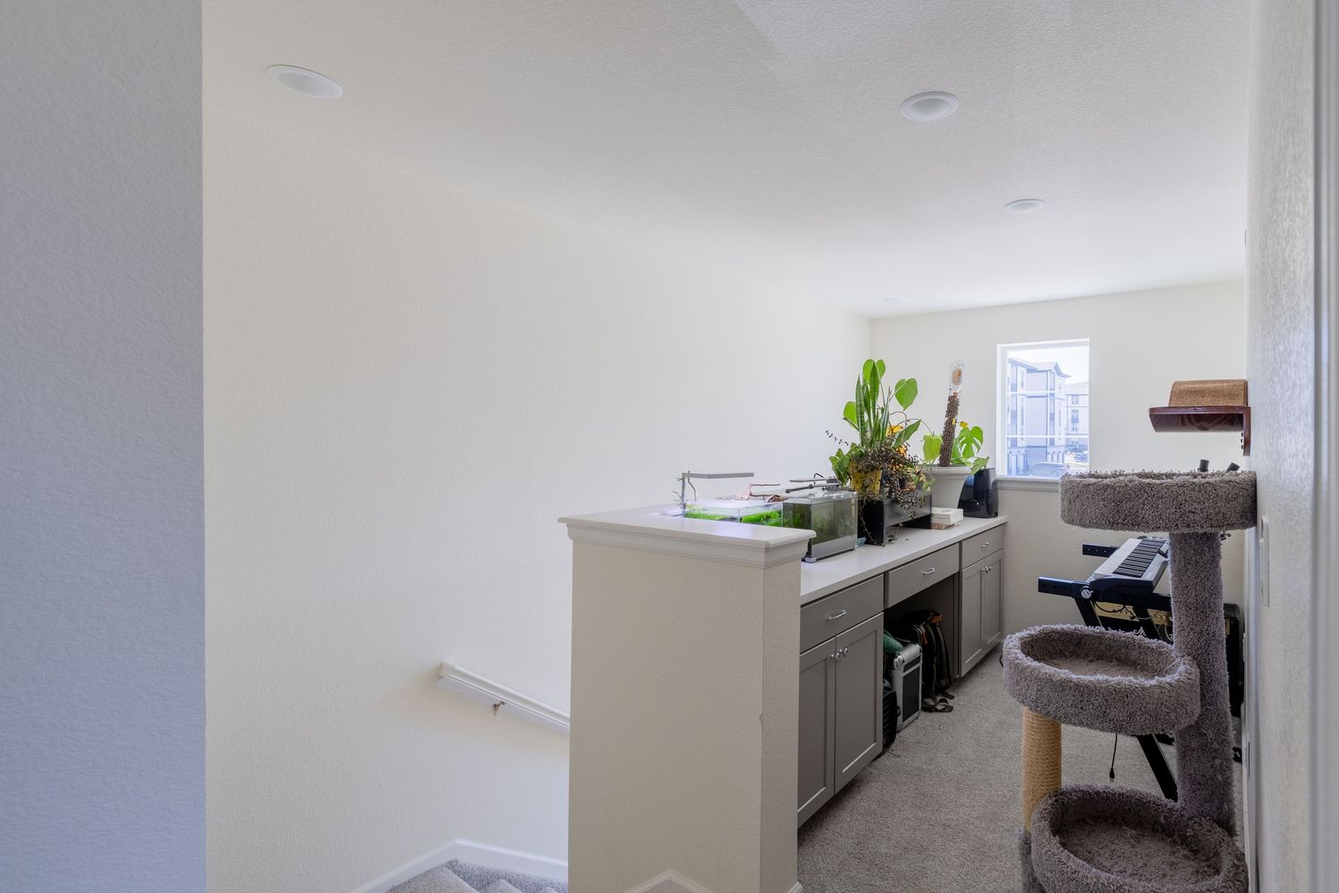 Bright open-concept room with gray built-in desk, shelving, and natural light from a window.