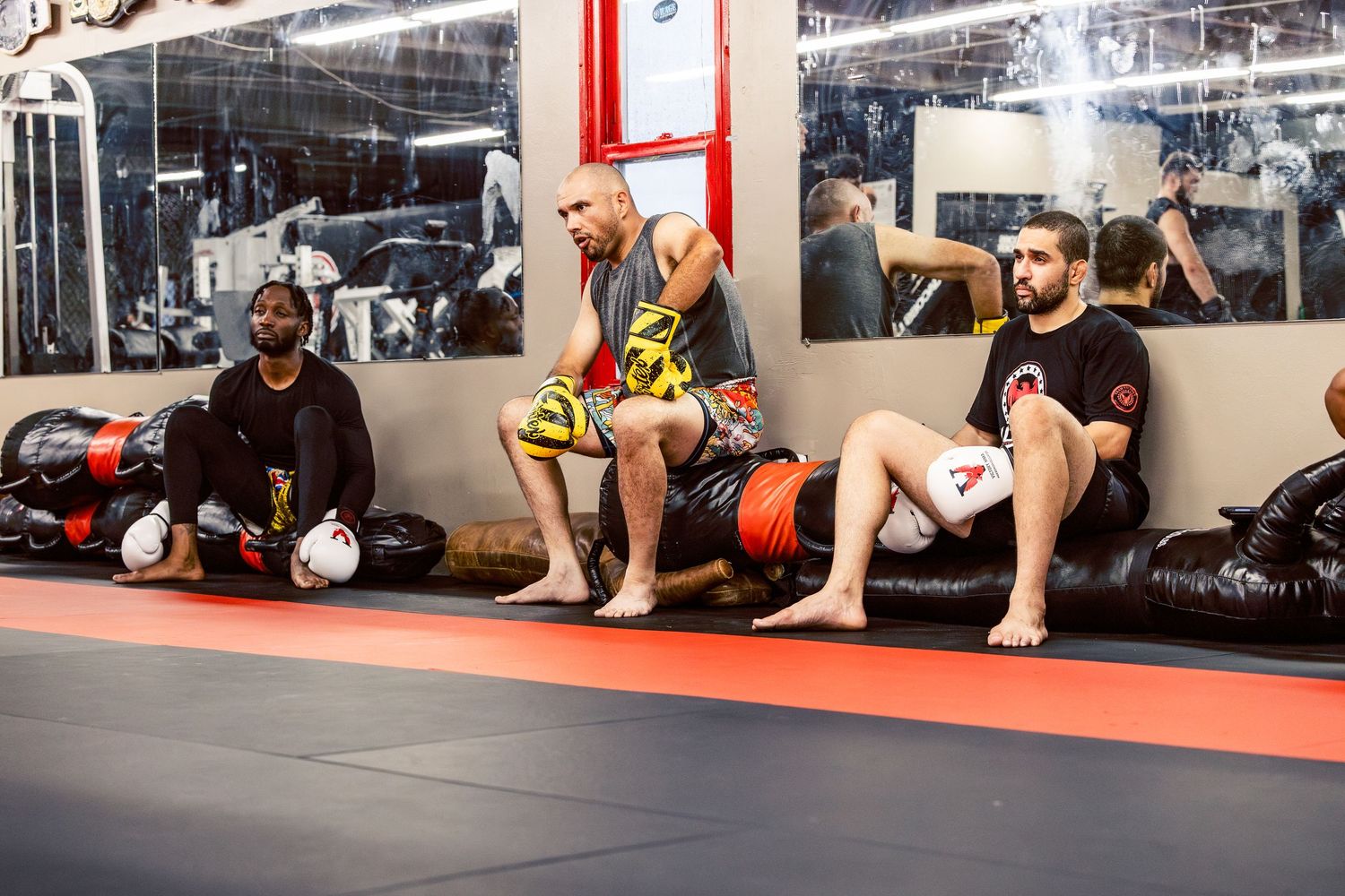 Wide view of martial arts students training along the gym wall.