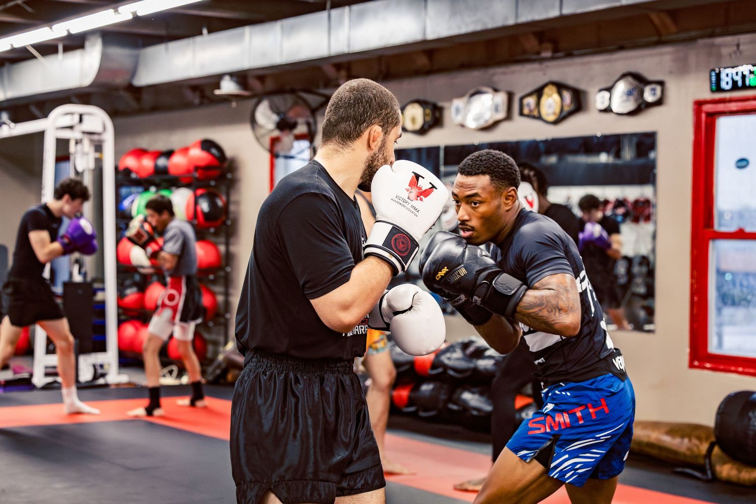 Mixed martial arts fighters practicing sparring techniques in a training facility.