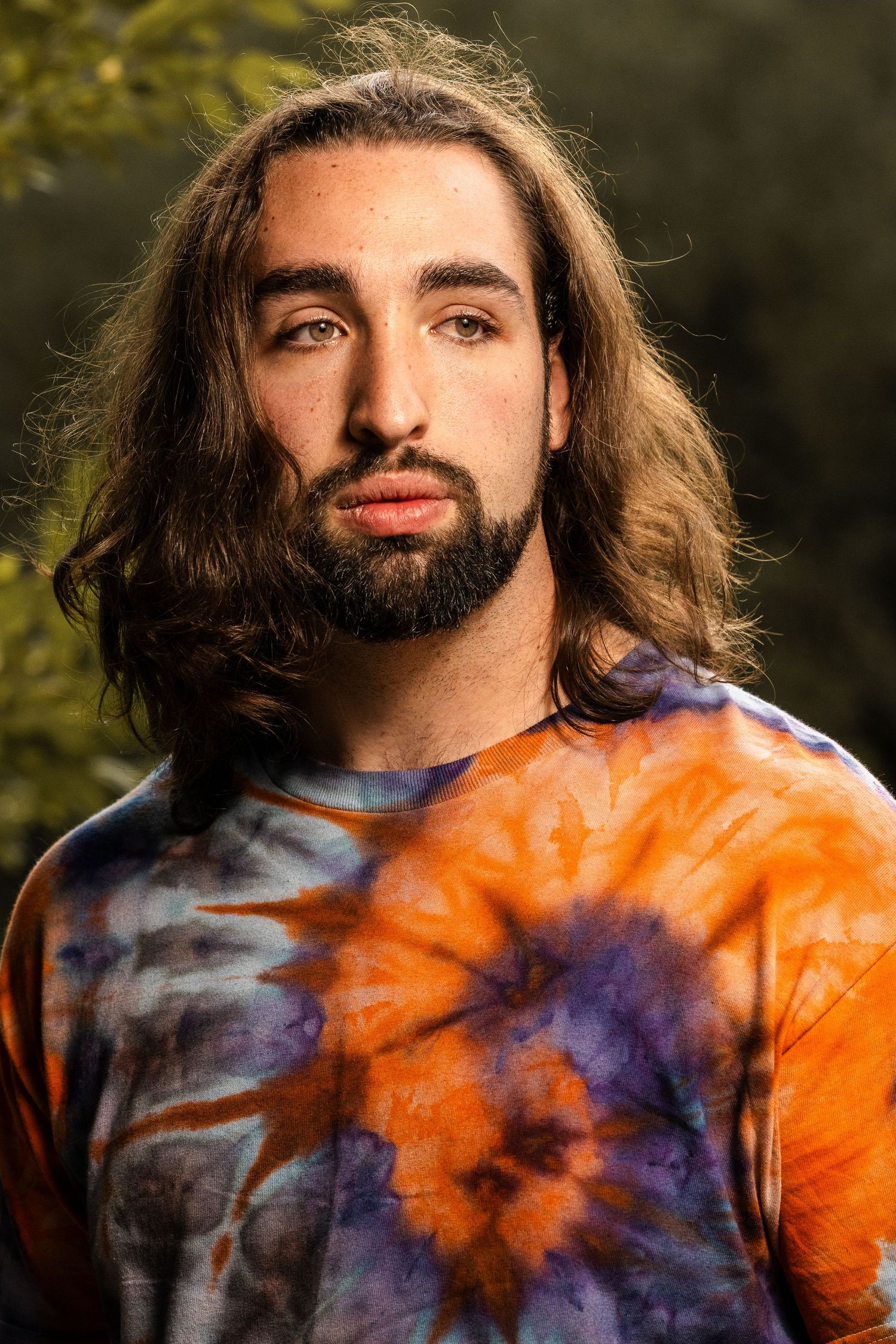 Close-up portrait showcasing a tie-dye shirt in orange and purple tones during golden hour.