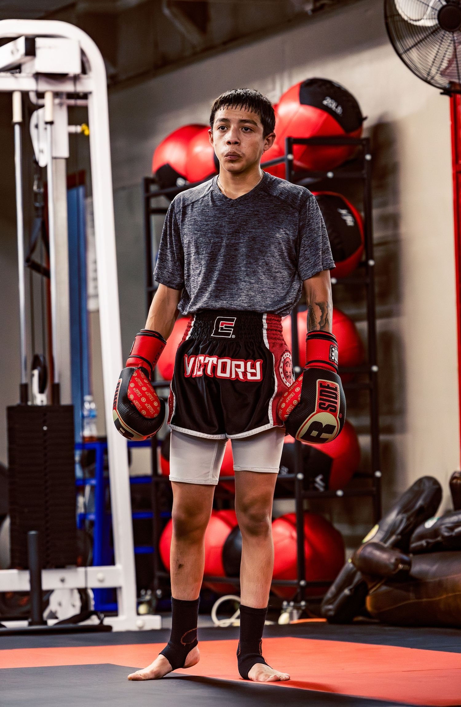 Martial arts student training with red boxing gloves on a gym mat.