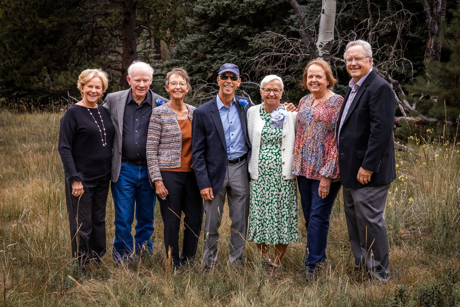 A group of people standing together outdoors in a natural setting with trees and grass in the background.