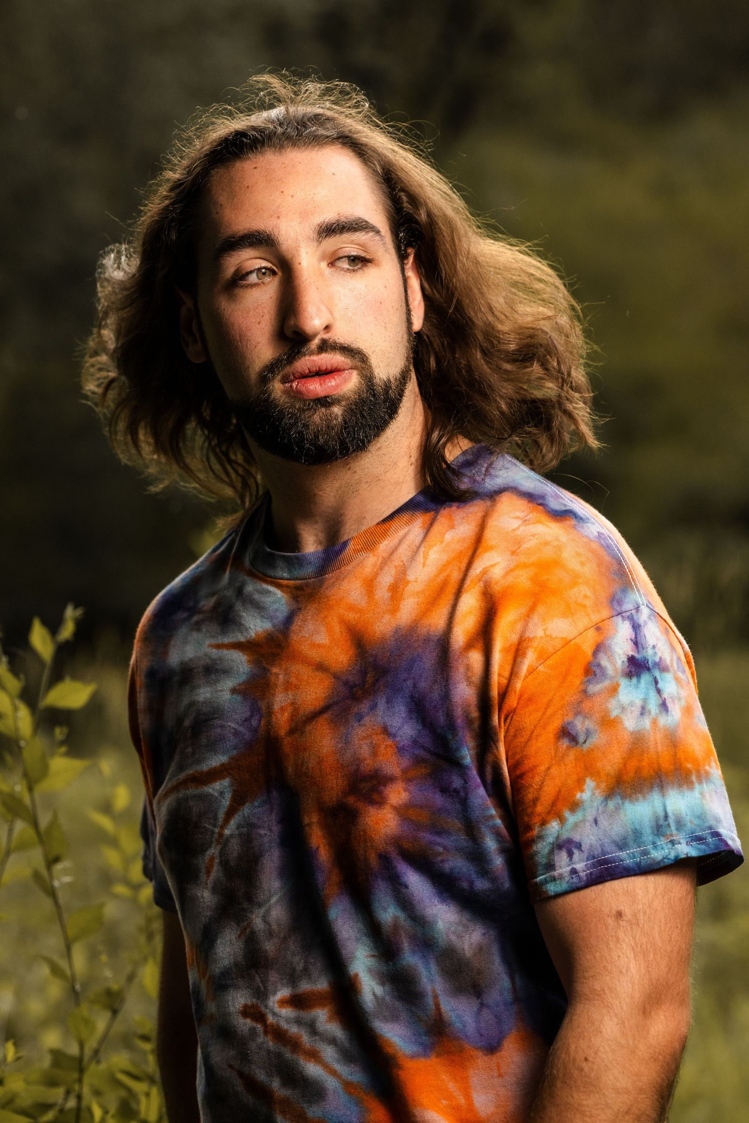 Golden hour portrait featuring someone wearing a vibrant orange and purple spiral tie-dye shirt.