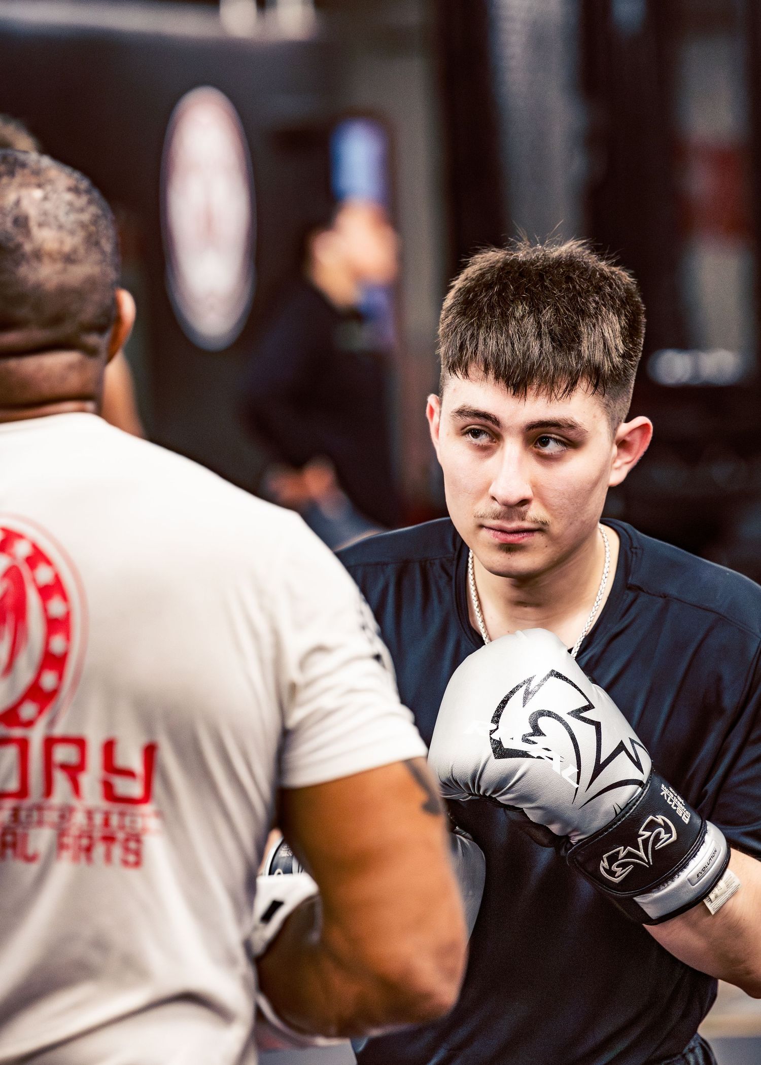 Boxer in black training gear practicing punches during a workout session at a gym.