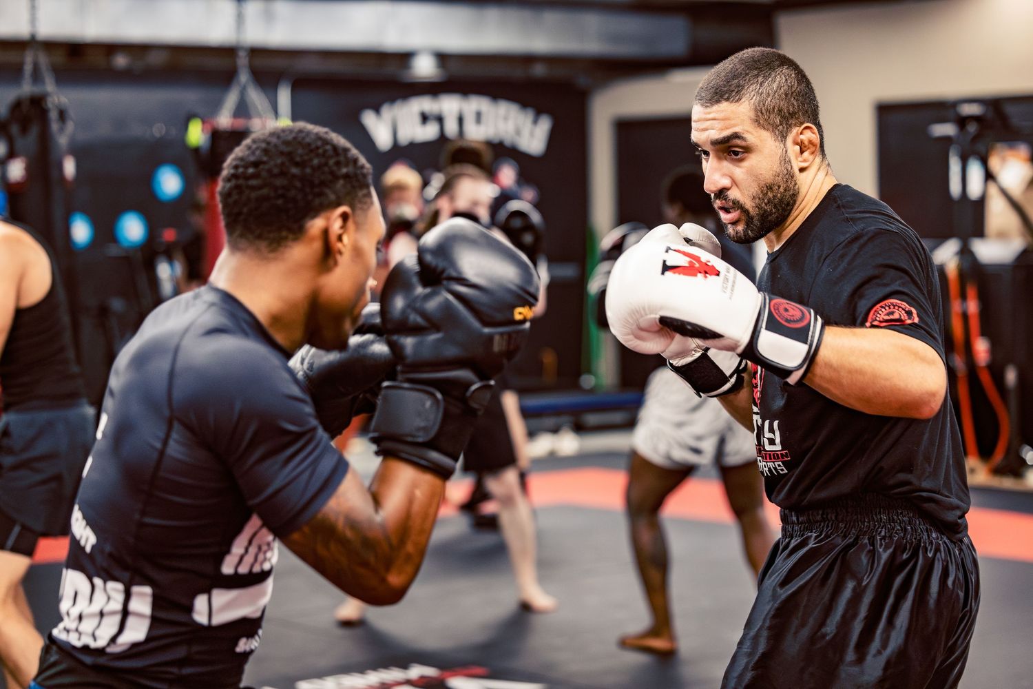 Boxing class participants practicing striking drills with partners in a professional gym setting.