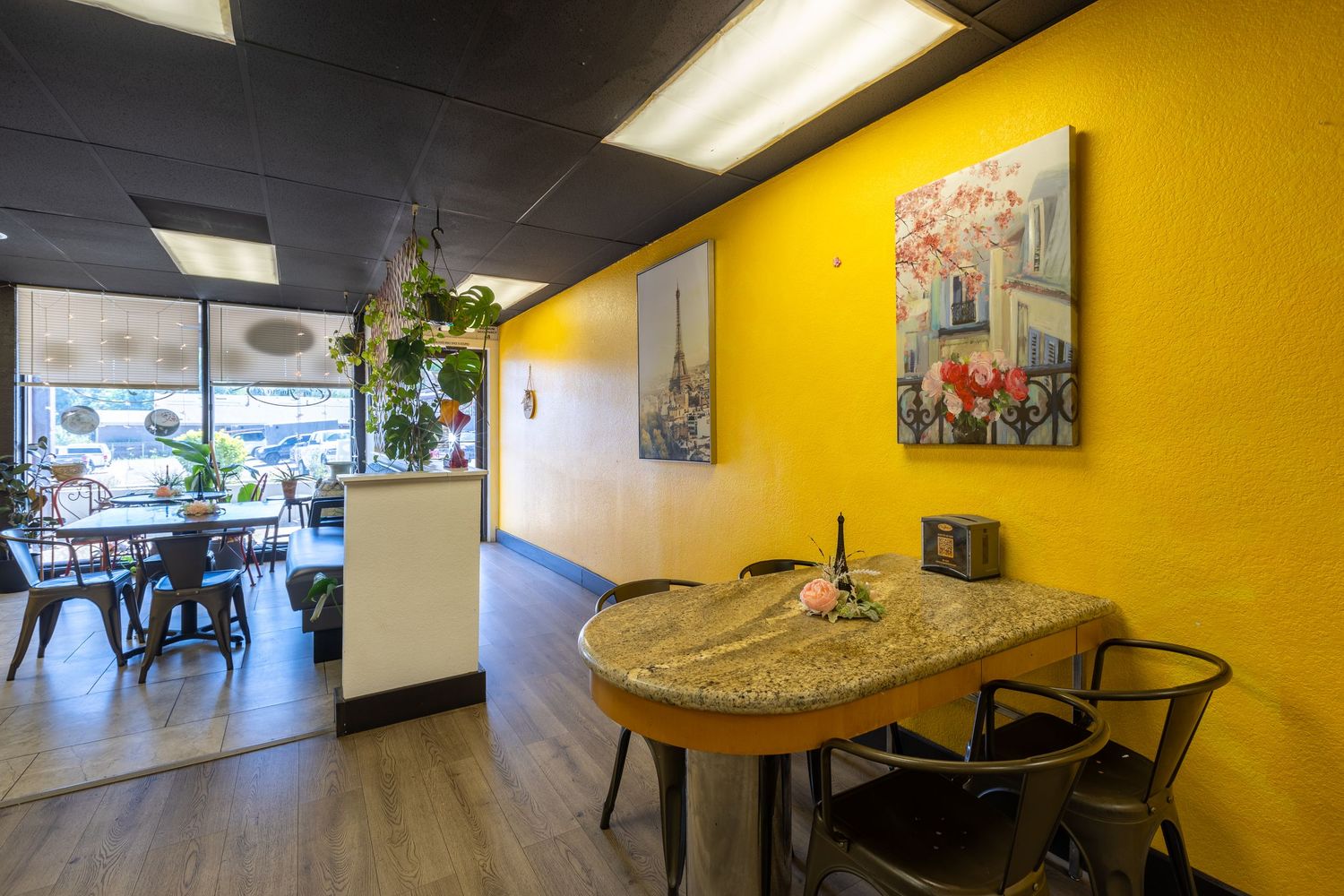 Bright yellow dining area with tables and Paris-themed artwork at a crepe cafe.