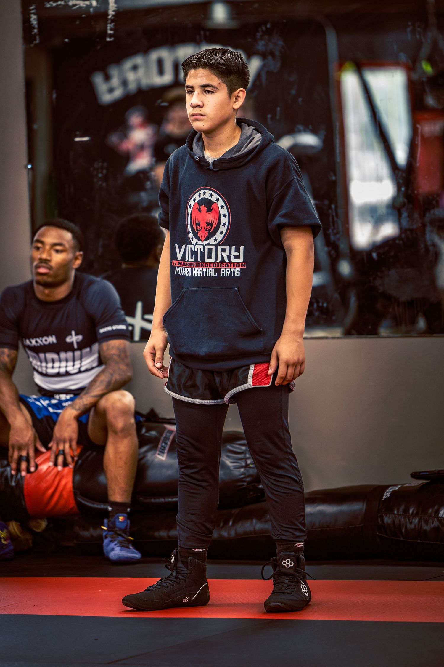 Athletes in athletic wear standing on red mats during a training session.