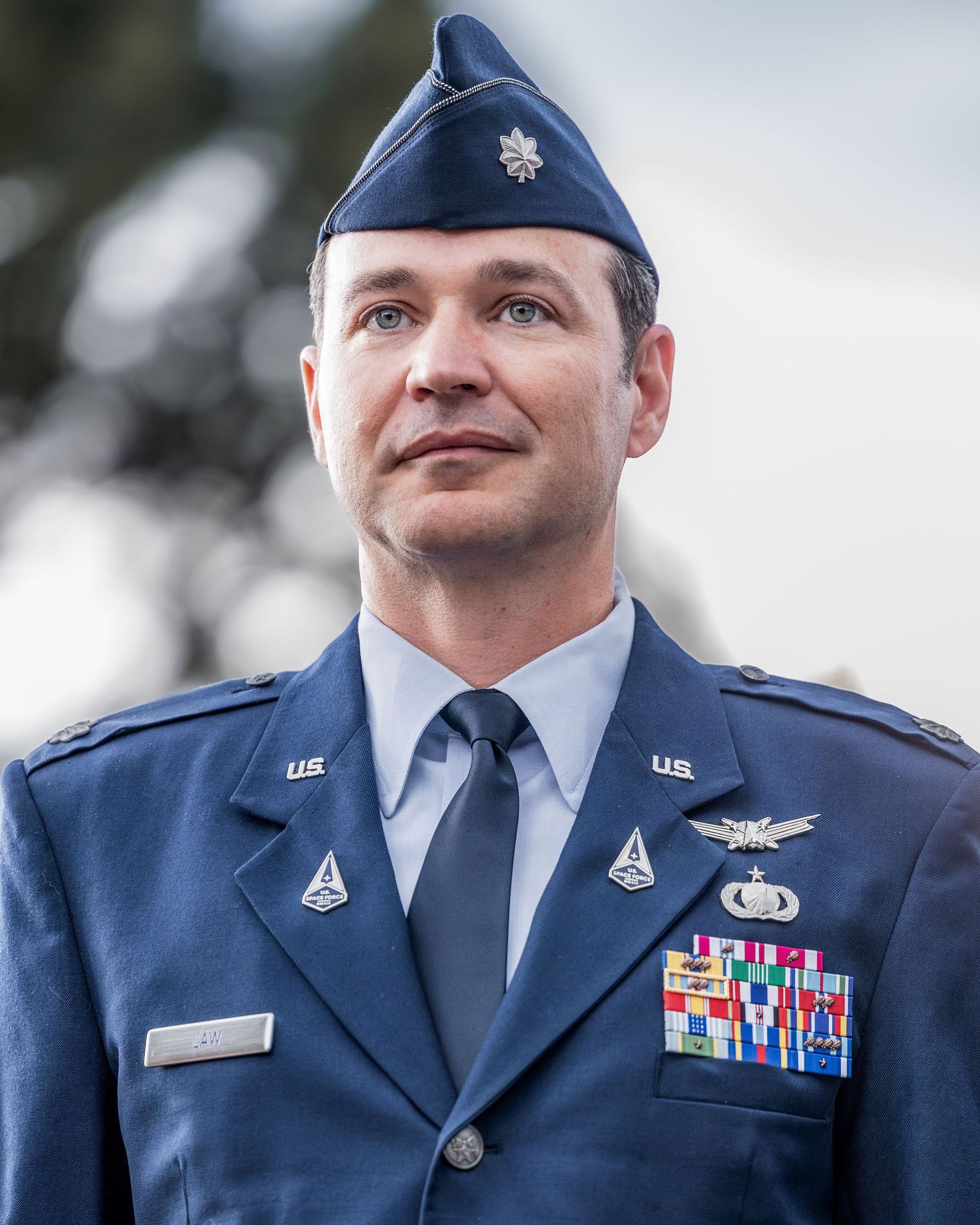 Air Force service member in dress blues with medals and ribbons during formal ceremony.