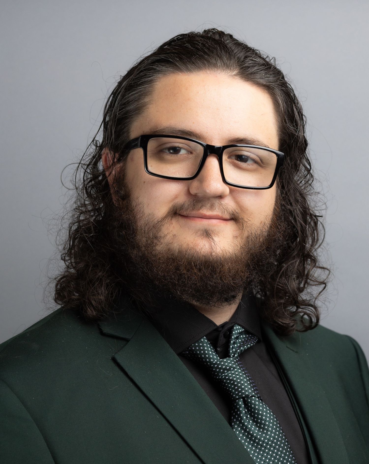 Professional headshot series with dark suit and polka dot tie against grey background.