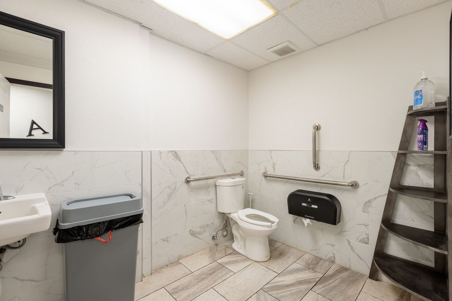 ADA-compliant accessible restaurant bathroom with marble tile walls, grab bars, and modern fixtures.