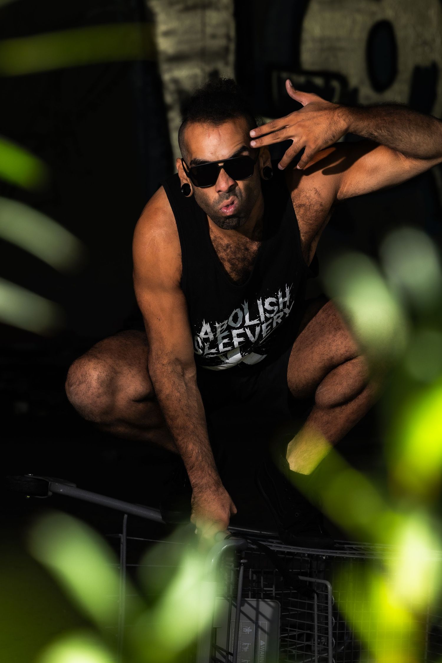 Athletic person in black tank top performing intense workout moves in dark setting with green lighting effects.