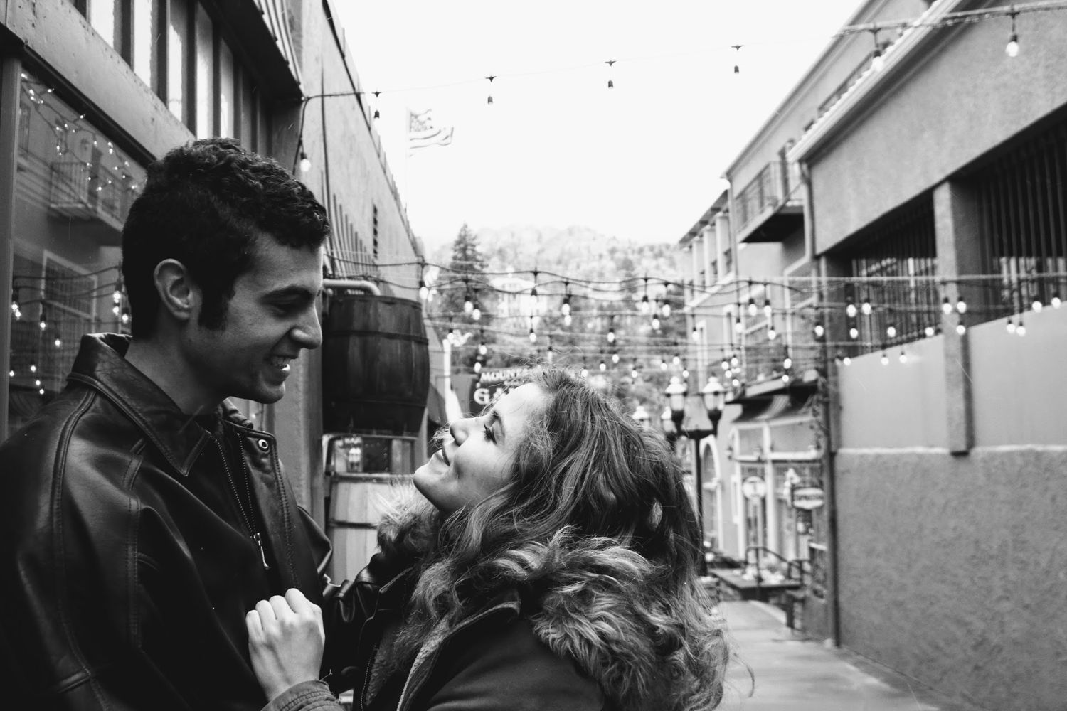 A series of black and white romantic photos showing a couple embracing against an urban backdrop.